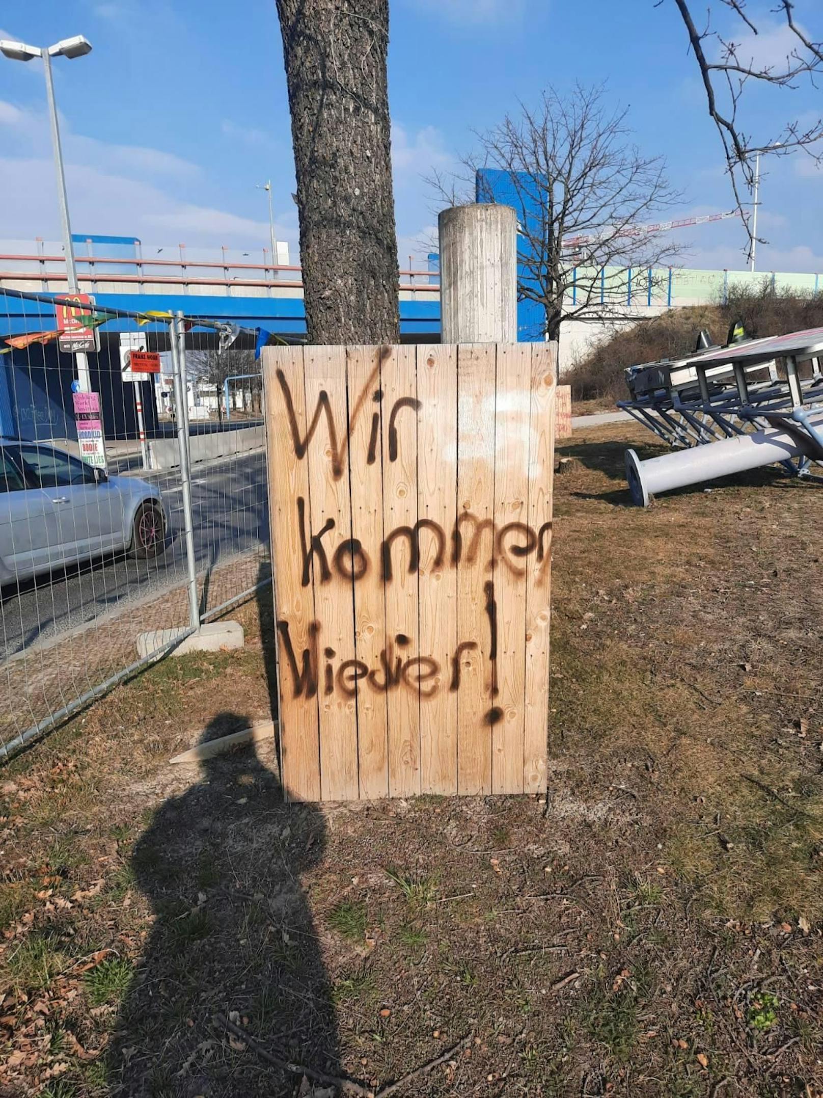 An einer Bretterwand die Drohung: "Wir kommen wieder!"