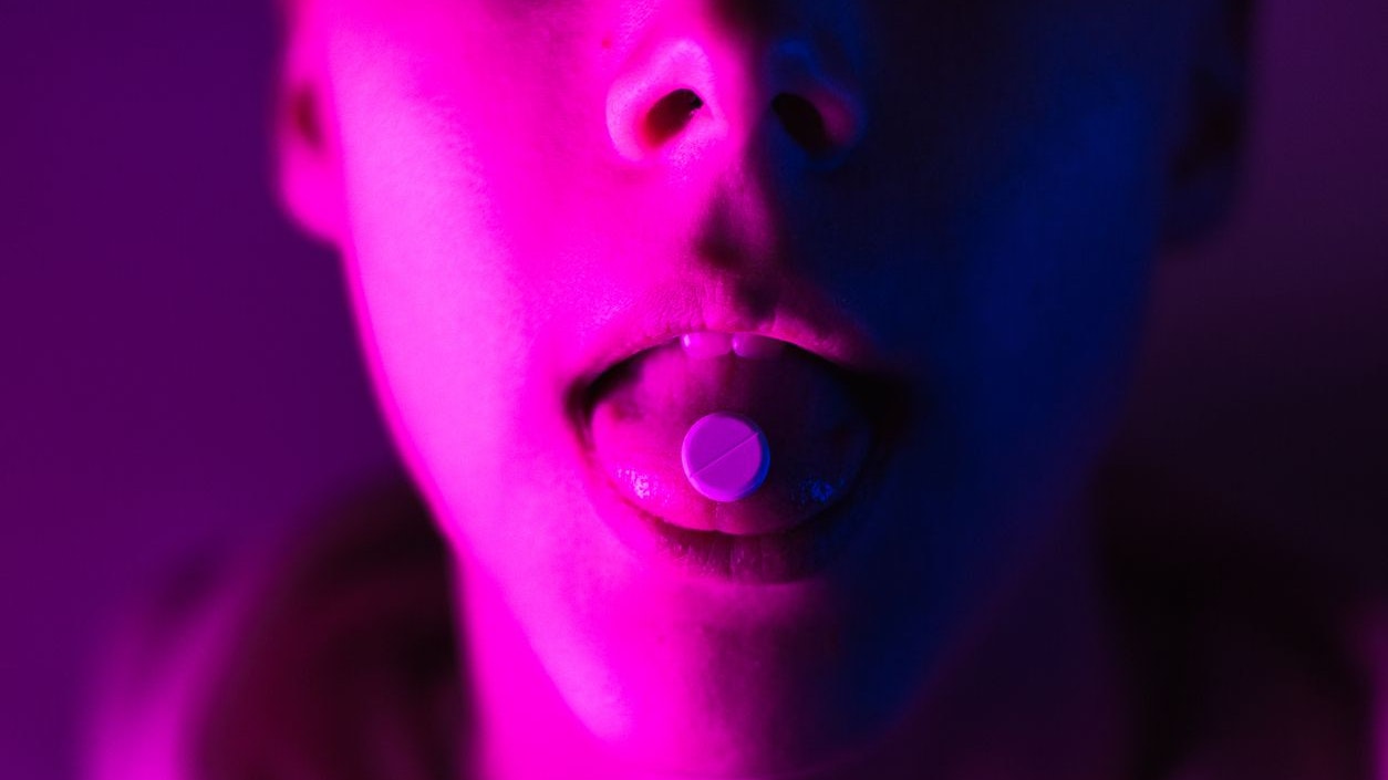 Young teenager in a pink hoodie takes a drug in pills. Tongue guy with lsd wheel.