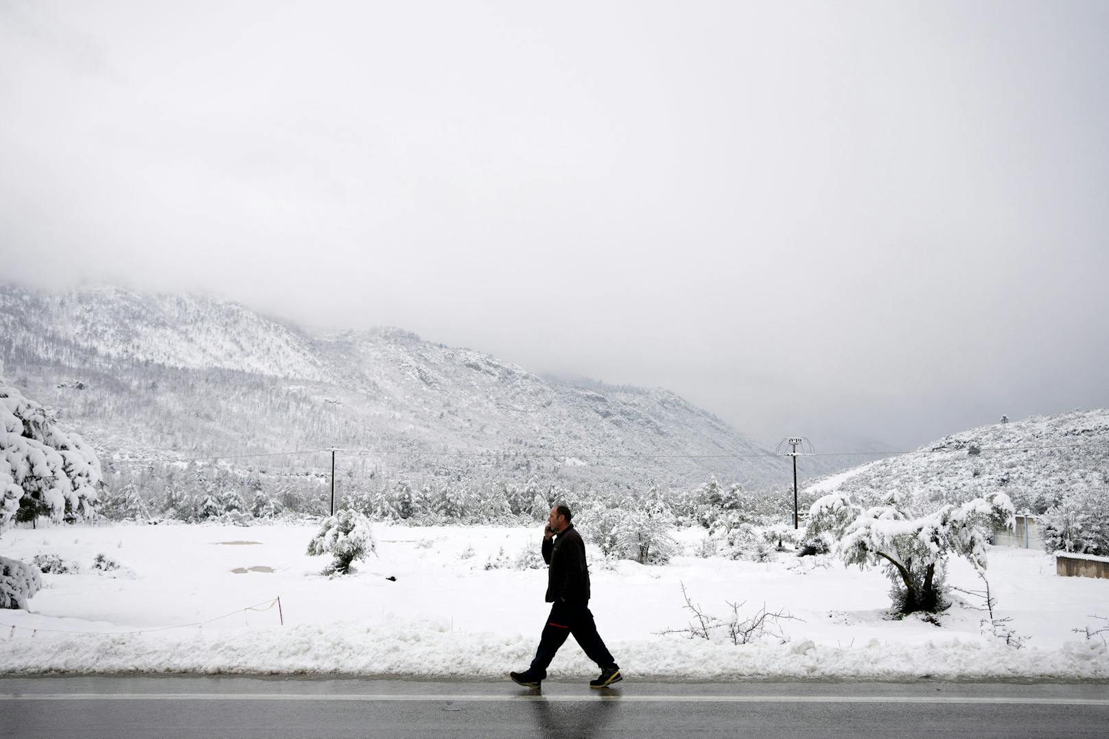 Die sonst so trockene Landschaft ist in dichtes weiß gehüllt. In der Ortschaft Malakasa wagt dieser Mann einen Spaziergang durch den Schnee.