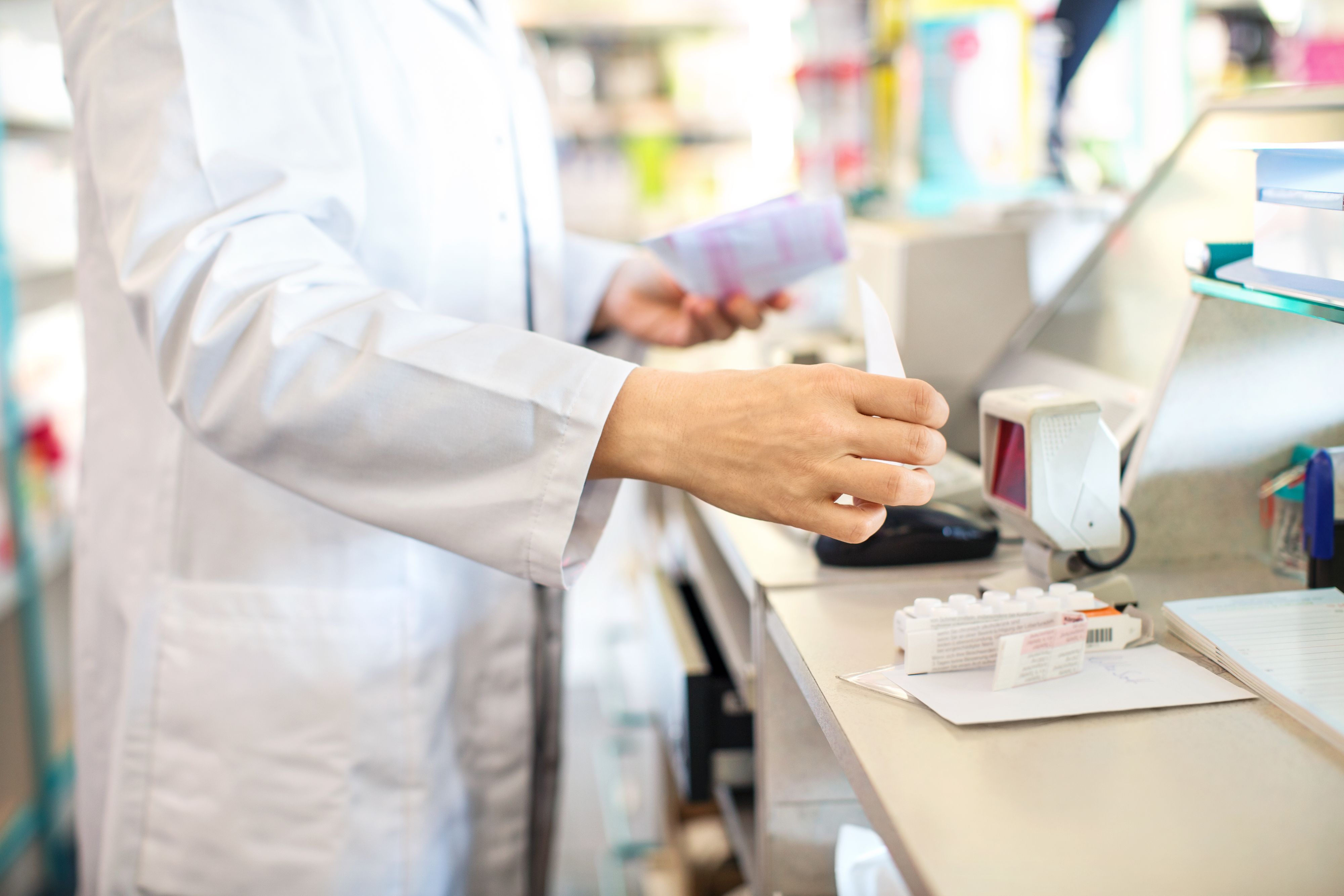Close up of pharmacist checking out customer's medication prescription