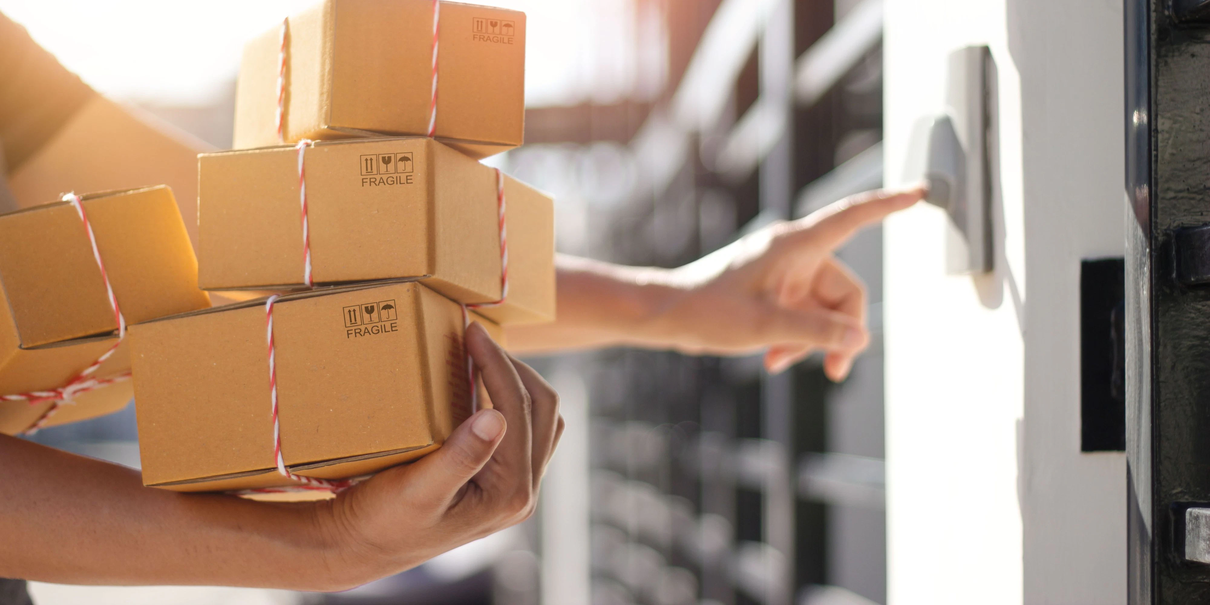 Delivery man holding parcel boxes and ring the doorbell on the client's door in the morning background.