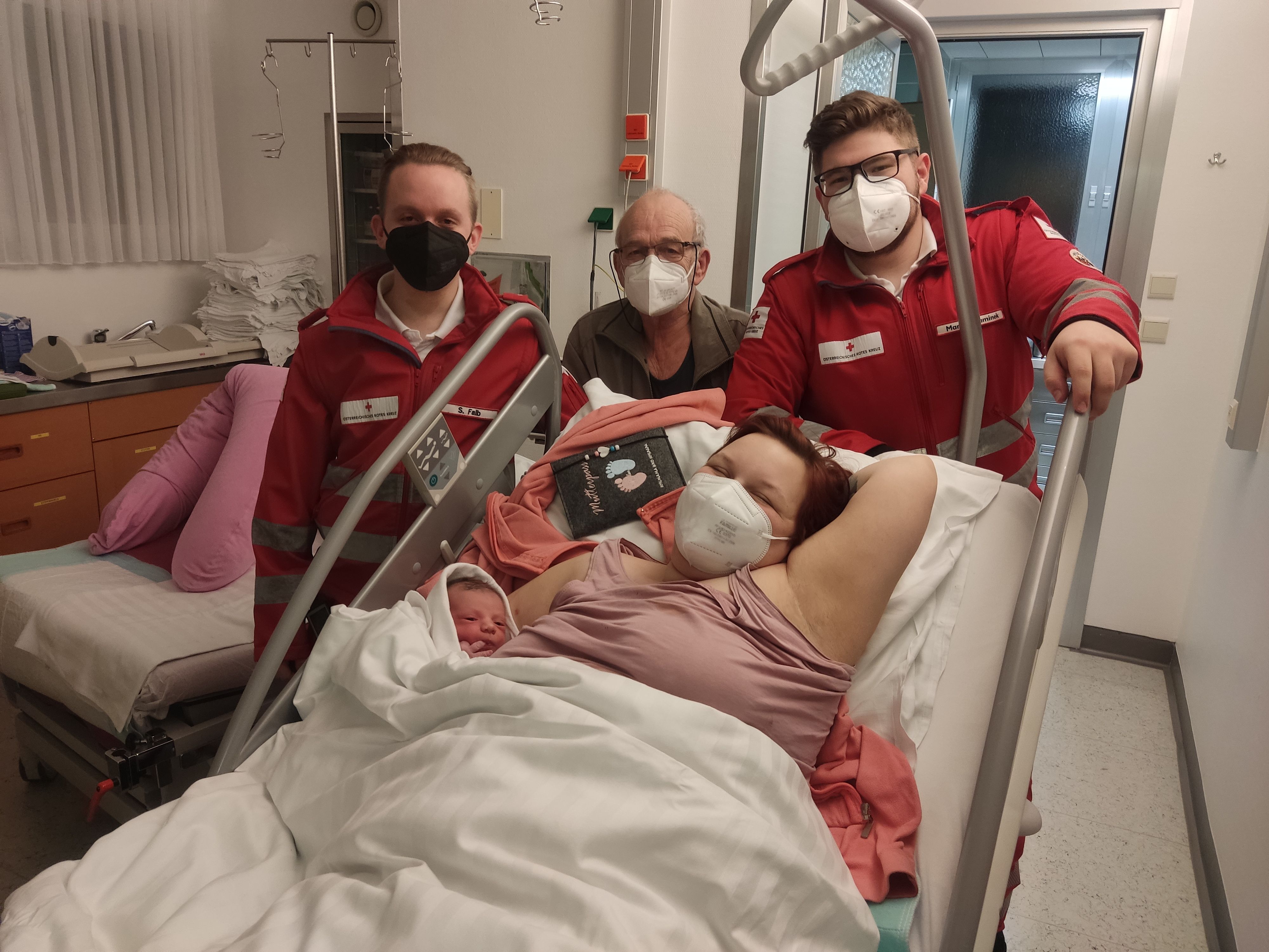 Die zweifache Mutter mit ihrer Laura-Aurelia in den Armen, hinter ihr stehend die Rettungsmannschaft und ihr Großvater