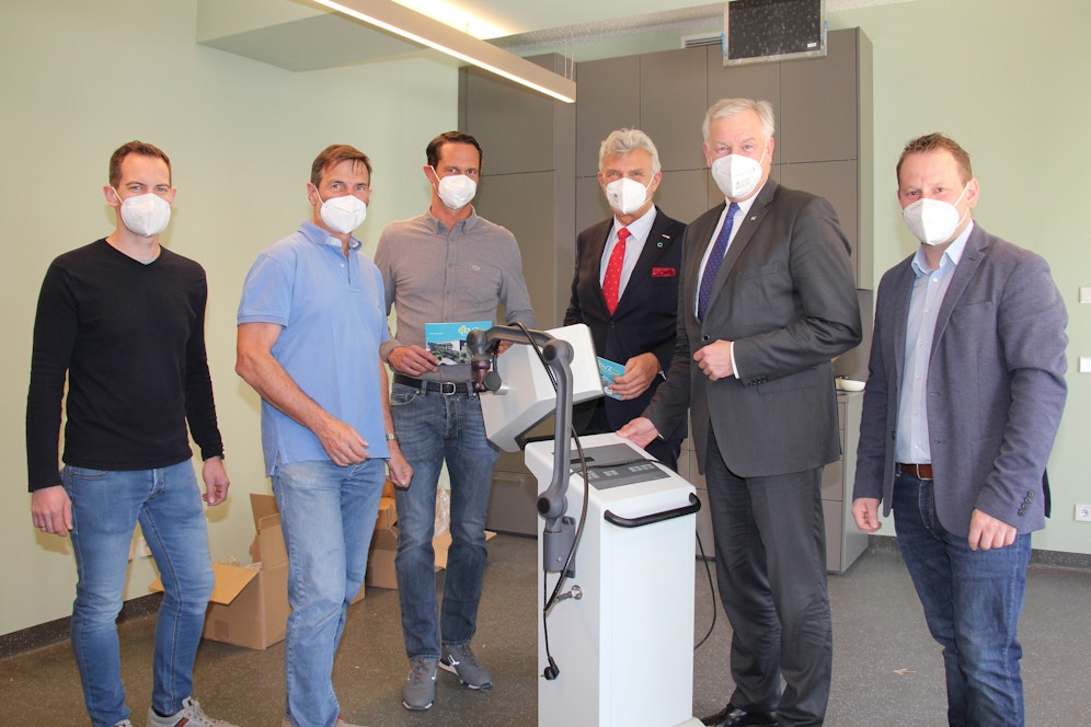 Dr. Thomas Bandur, Dr. Leopold Auer, Geschäftsführer Philipp Schramhauser, Norbert Fidler, Vorsitzender des Landesstellenausschusses der Österreichischen Gesundheitskasse in Niederösterreich, Landesrat und NÖGUS-Vorsitzender Martin Eichtinger und Bürgermeister Harald Riemer hinter einem Kurzwellengerät zur Wärmetherapie bzw. zum Aufwärmen vor einer Massage.
