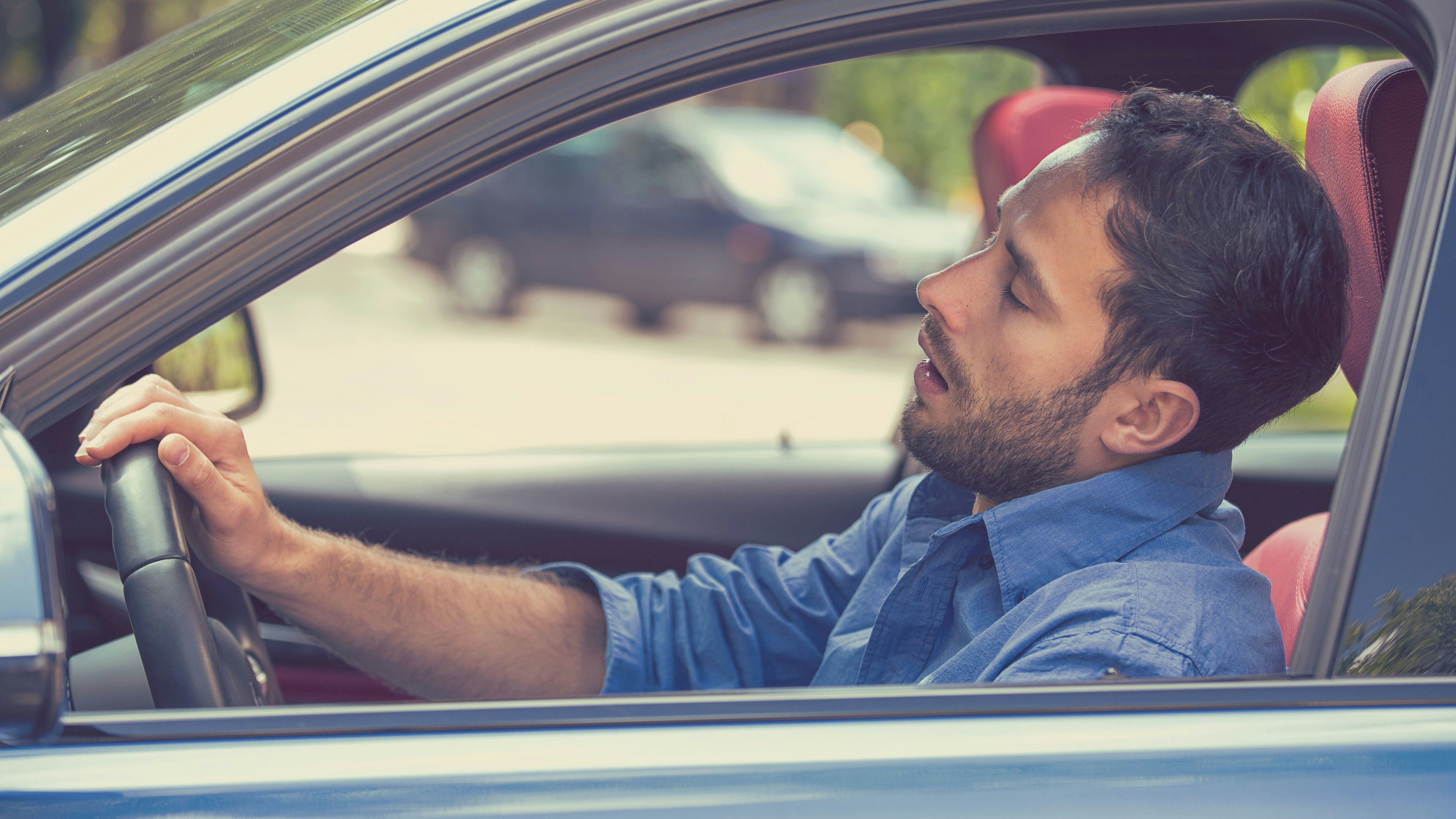 Side view window sleepy tired fatigued exhausted young man driving his car in traffic after long hour drive. Transportation safety sleep deprivation accident concept
