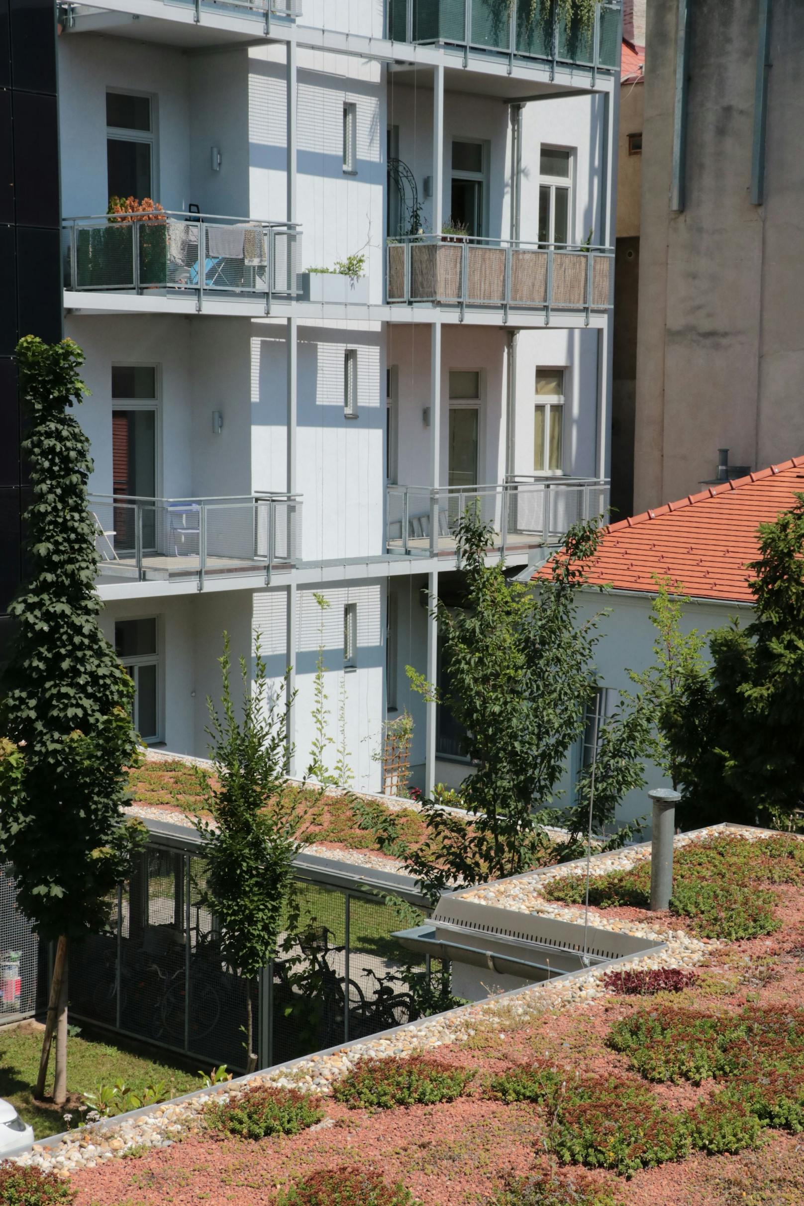 Photovoltaik-Element an der Liftfassade, Dachbegrünung und Grünflächen im Innenhof.