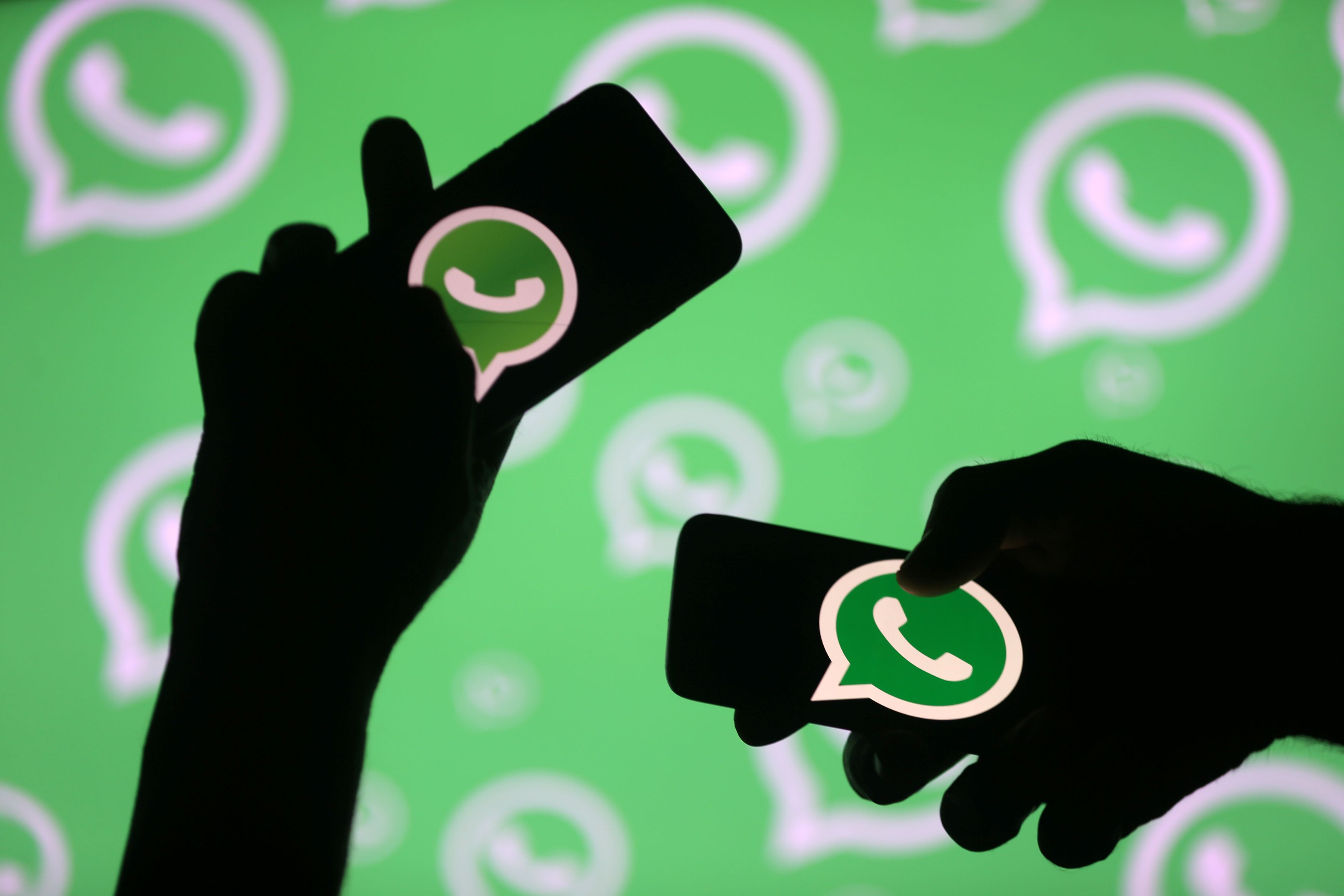 Men pose with smartphones in front of displayed Whatsapp logo in this illustration September 14, 2017. REUTERS/Dado Ruvic