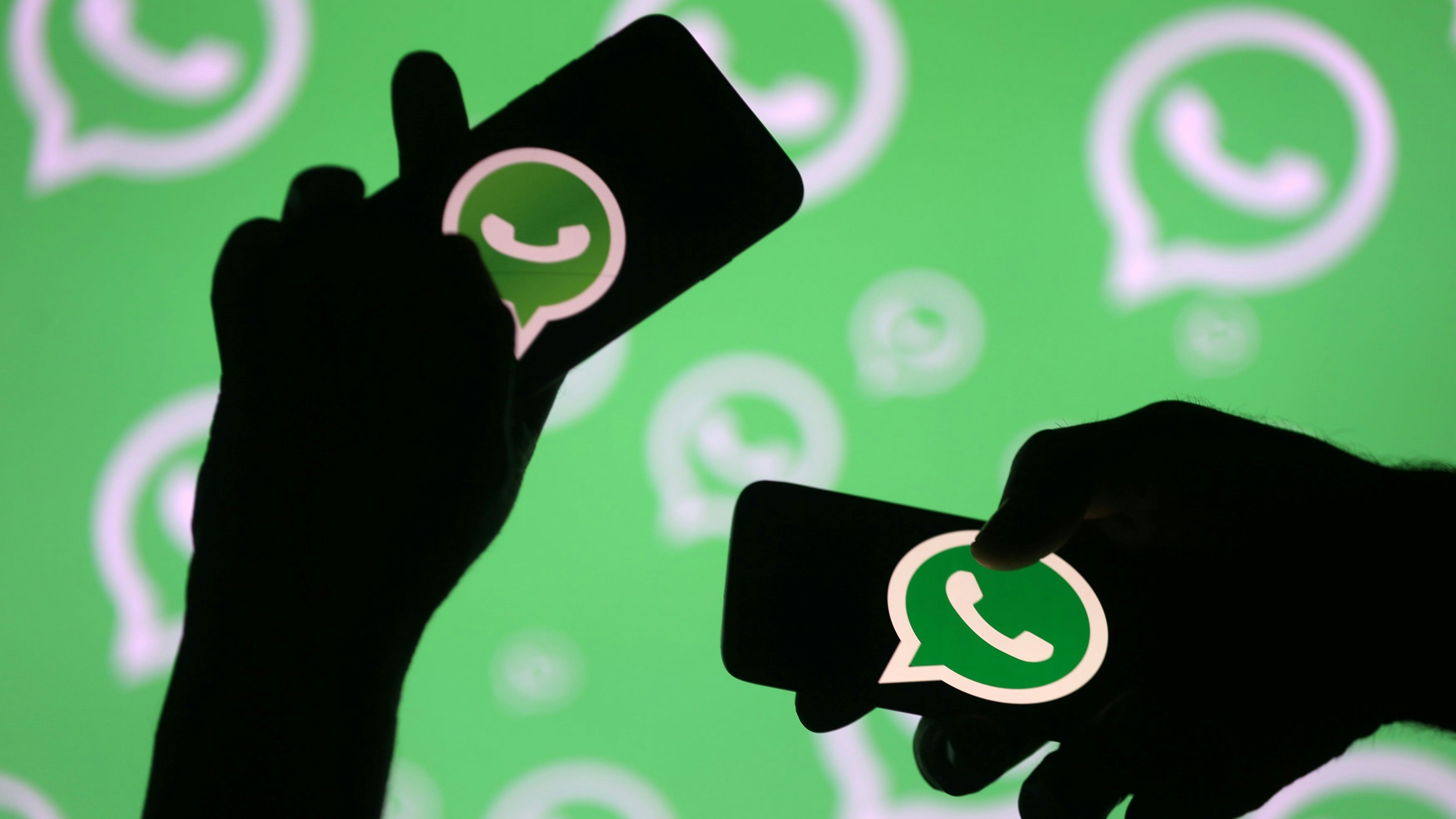 Men pose with smartphones in front of displayed Whatsapp logo in this illustration September 14, 2017. REUTERS/Dado Ruvic
