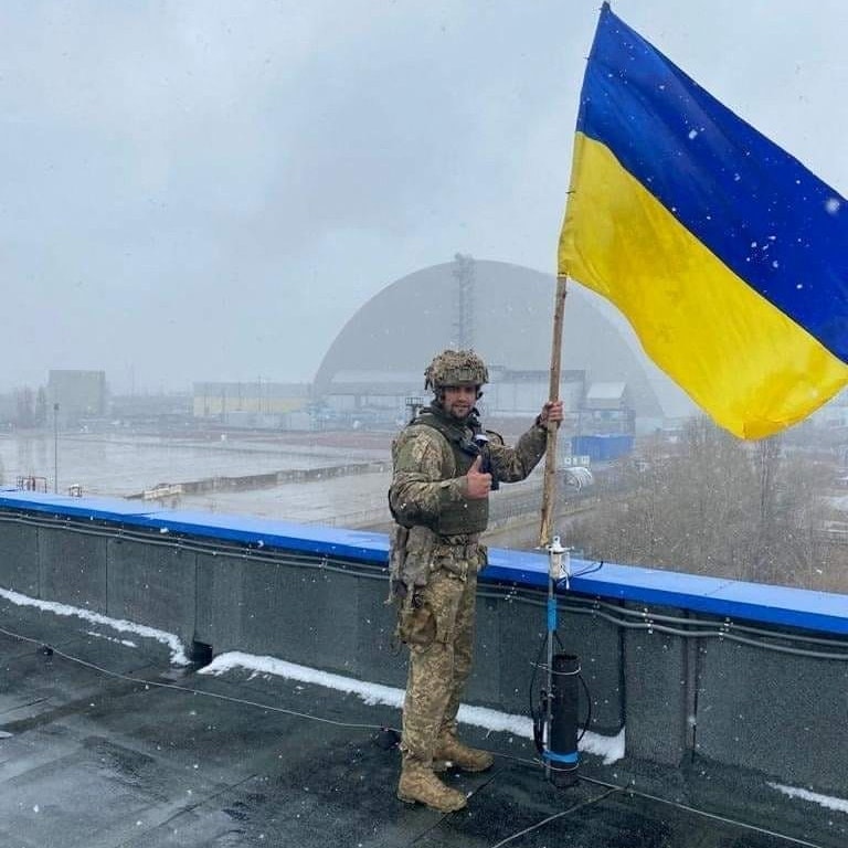 A Ukrainian service member installs the Ukrainian national flag at a compound of the Chornobyl Nuclear Power Plant, as Russia's attack on Ukraine continues, in Ukraine, in this handout picture released April 3, 2022. Press service of the Ukrainian Armed Forces General Staff/Handout via REUTERS  ATTENTION EDITORS - THIS IMAGE HAS BEEN SUPPLIED BY A THIRD PARTY.