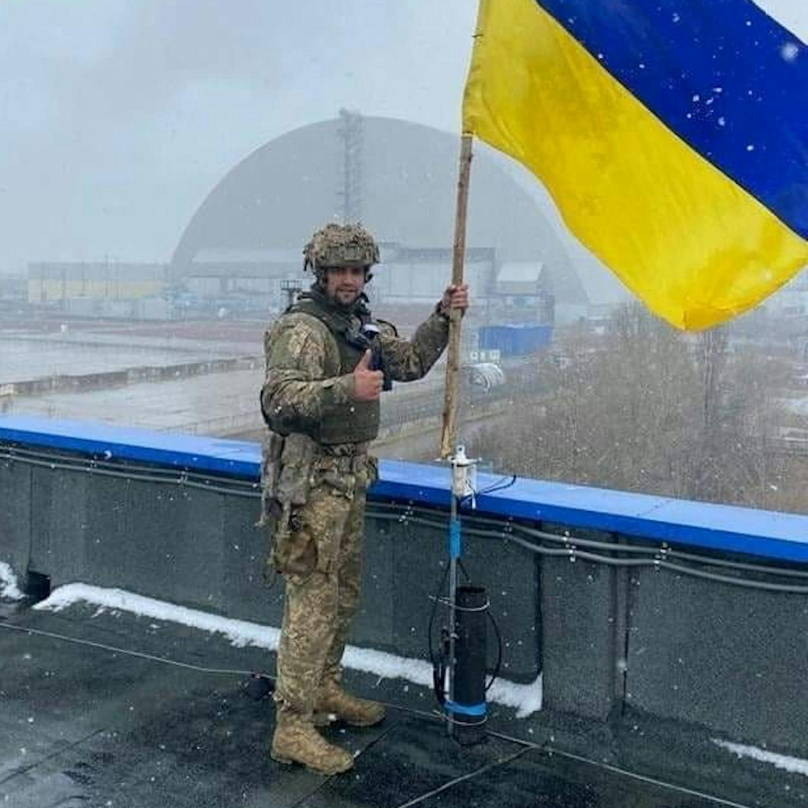 Ein fröhlicher Soldaten samt ukrainischen Flagge und Daumen-hoch-Pose vor dem rückeroberten AKW Tschernobyl.