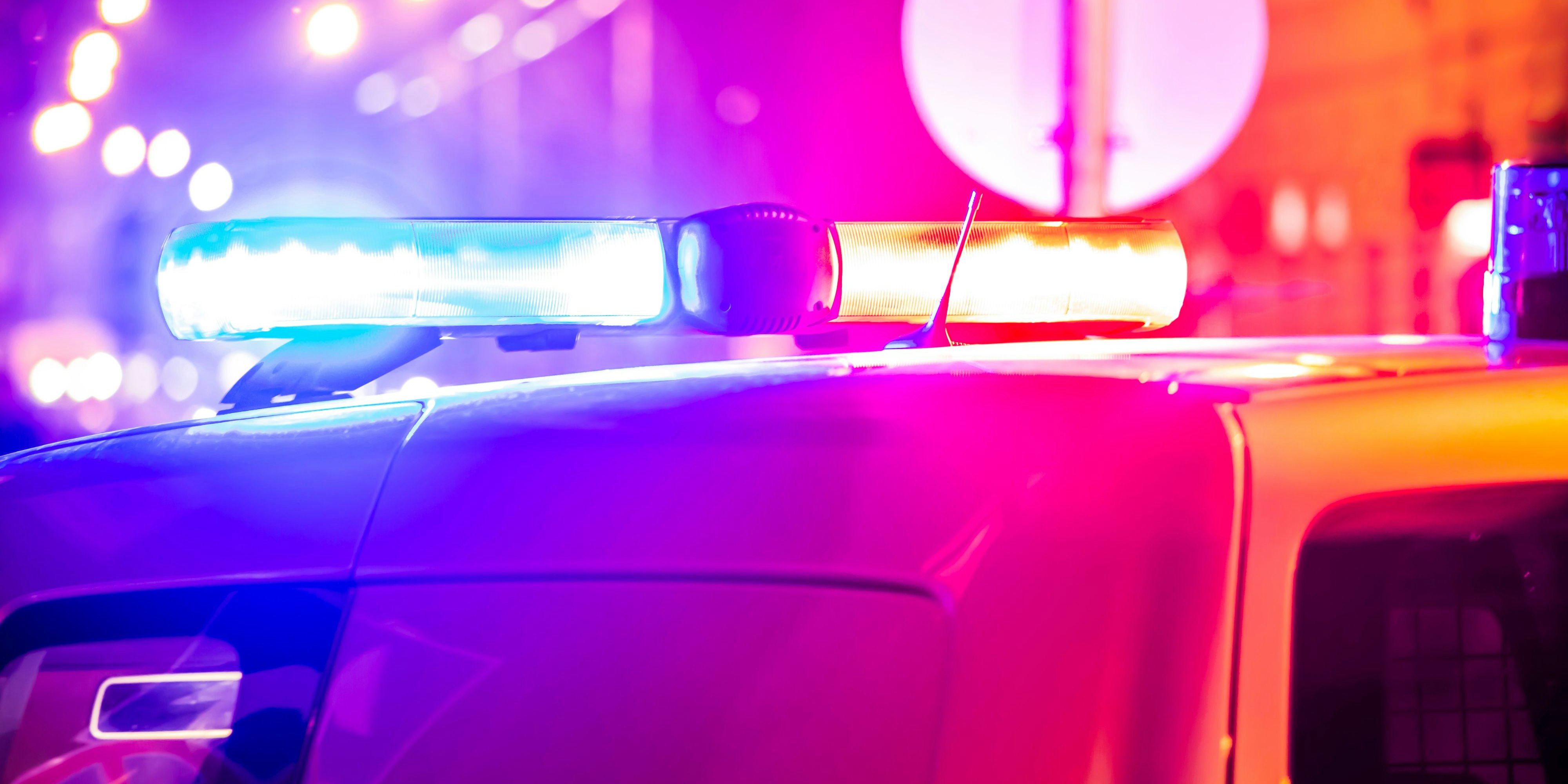 Police car in action with blinking light and siren signal at night in the city. Blurred bokeh background, public lighting lamps.