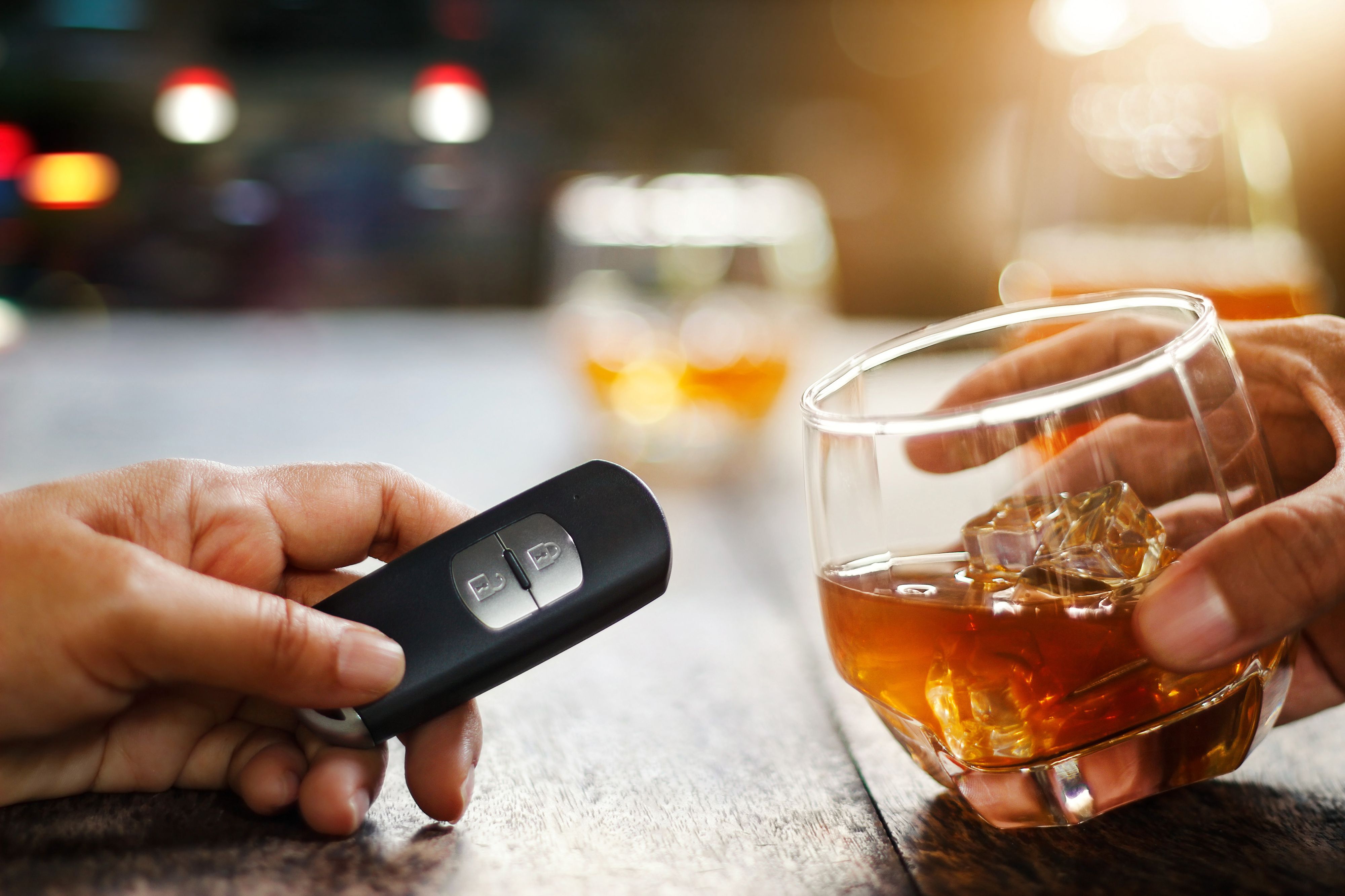 Hand holding alcoholic drink, another hold car remote, Drunk driving concept.