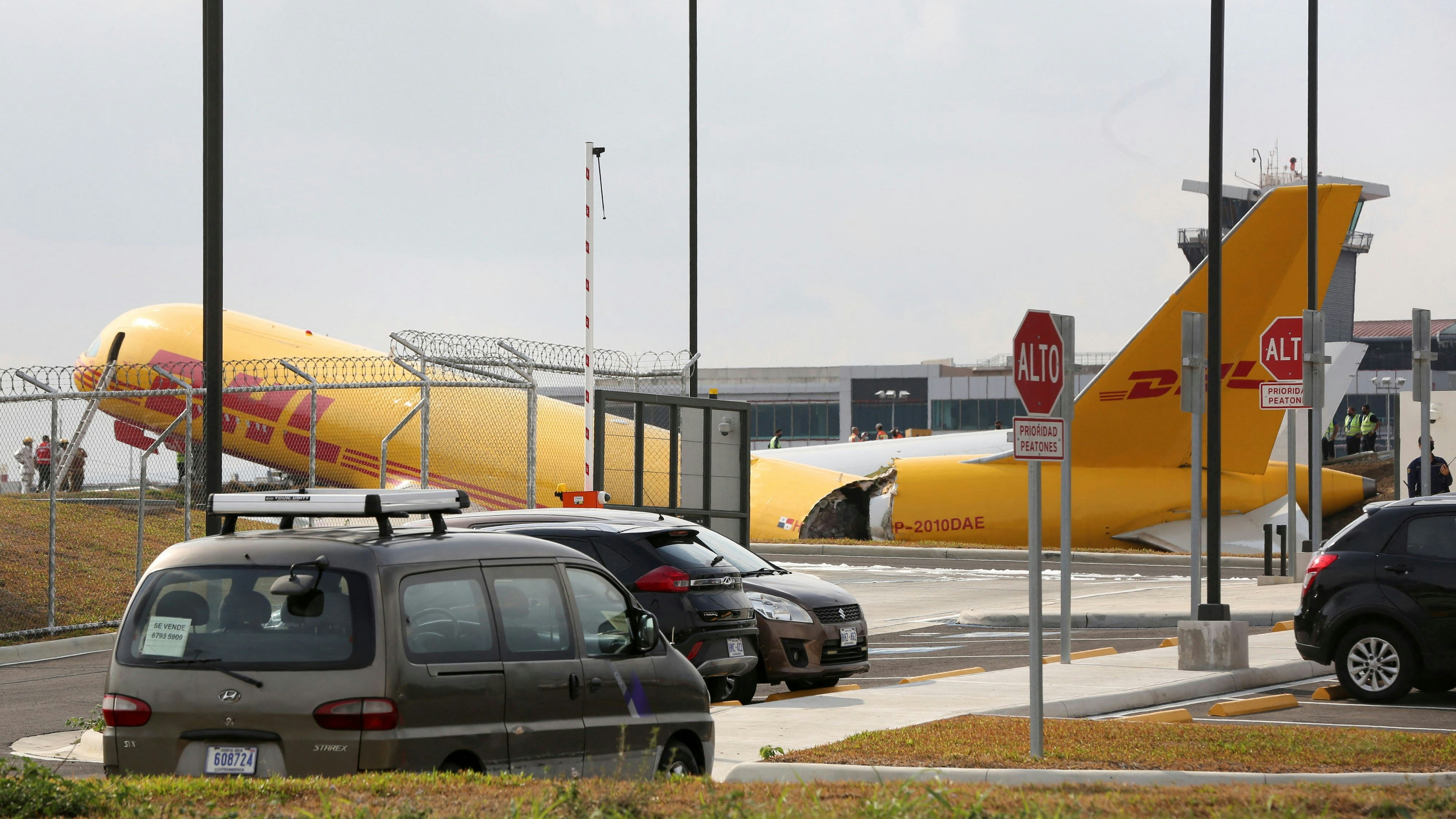 Airport personnel stand at the scene where a Boeing 757-200 cargo aircraft operated by DHL made an emergency landing before skidding off the runway and splitting, aviation authorities said, at the Juan Santamaria International Airport in Alajuela, Costa Rica April 7, 2022. REUTERS/Mayela Lopez