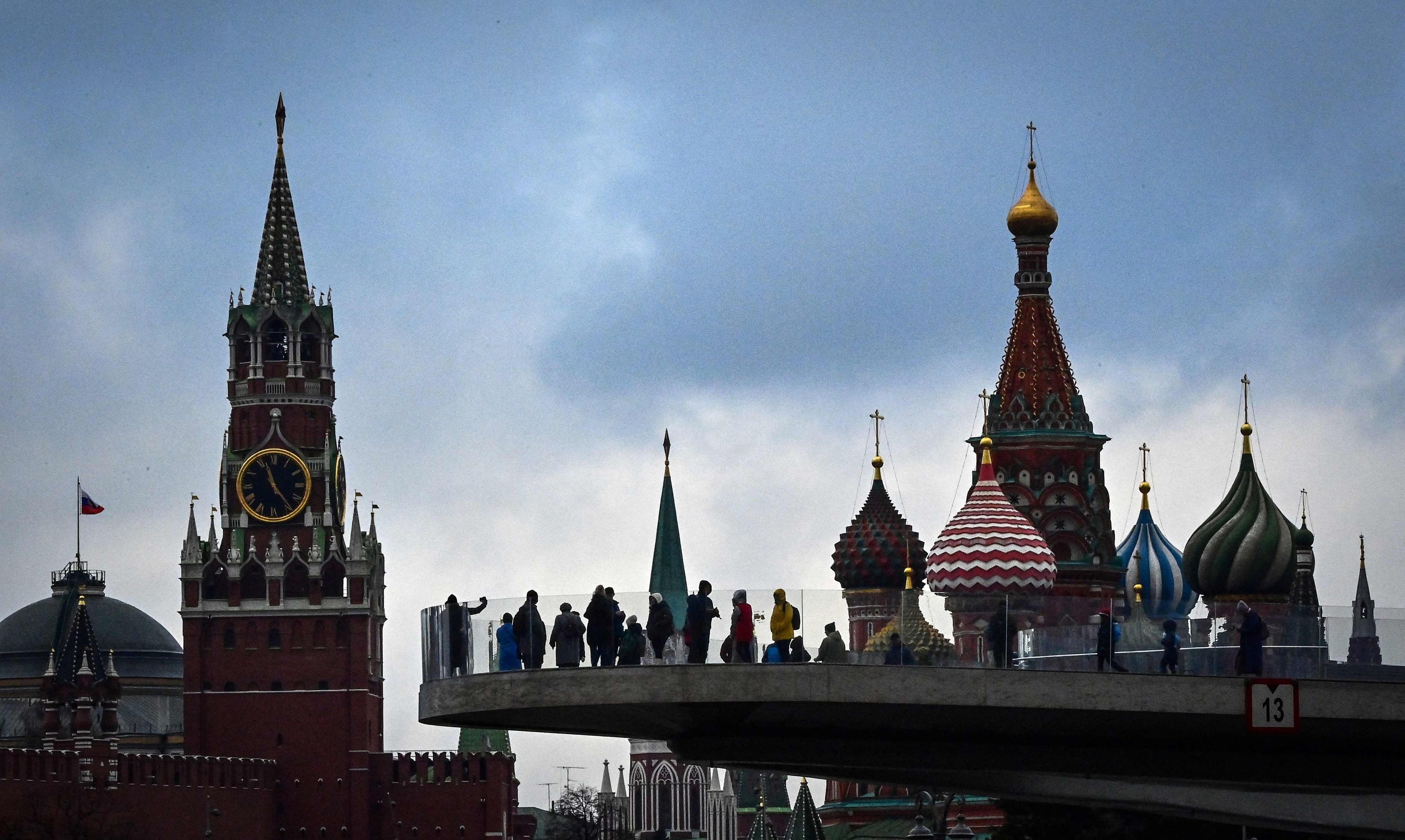 Download von www.picturedesk.com am 12.04.2022 (12:09).  (FILES) This file photograph taken on November 4, 2021, shows pedestrians as they walk on a bridge in the Zaryadye park in central Moscow, with Kremlin's Spasskaya tower and Saint-Basil Cathedral in the background. - Like many members of Russia's affluent middle class, advertising producer Rita Guerman had long opposed Kremlin strongman Vladimir Putin. But punishing Western sanctions following Putin's decision to send troops to Ukraine in late February has changed her opinion of the Russian leader. "I have opened my eyes," said the 42-year-old brunette, praising the Russian president for defending the country "against NATO". (Photo by AFP) - 20220411_PD3250 - Rechteinfo: Rights Managed (RM) Nur für redaktionelle Nutzung! Werbliche Nutzung erfordert Freigabe: bitte schicken Sie uns eine Anfrage.