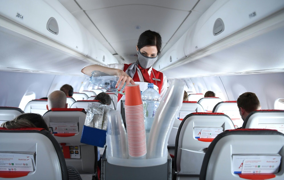 Eine AUA-Stewardess beim Austeilen von Getränken (Symbolfoto)