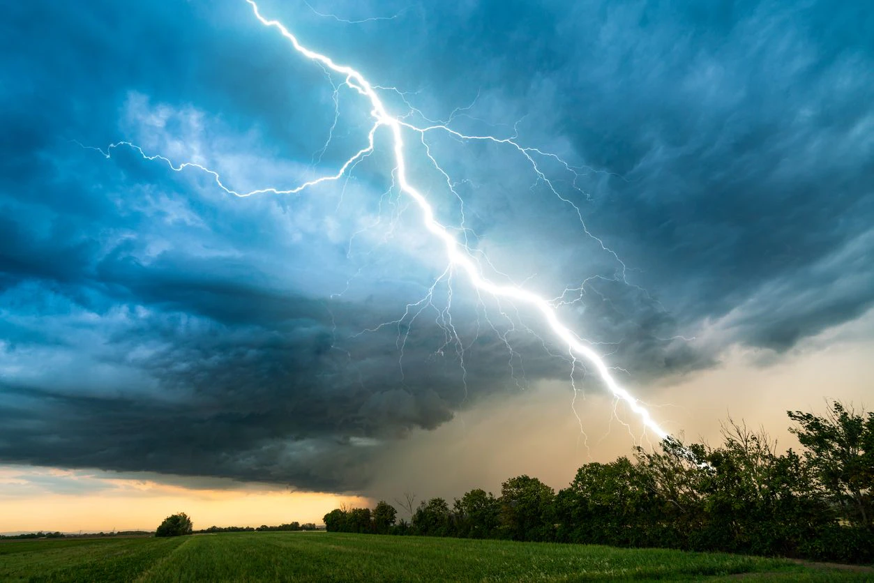 dramatic lightning thundertbolt bolt strike in daylight rural surrounding bad weather dark sky