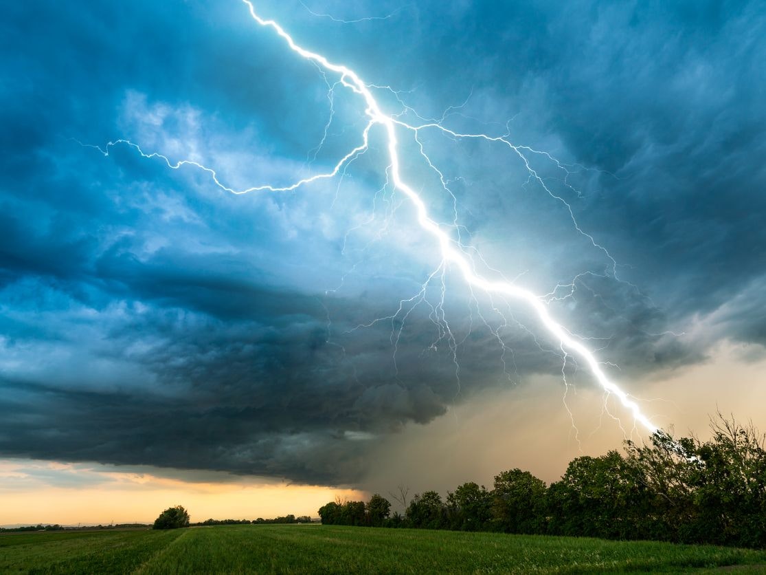 dramatic lightning thundertbolt bolt strike in daylight rural surrounding bad weather dark sky