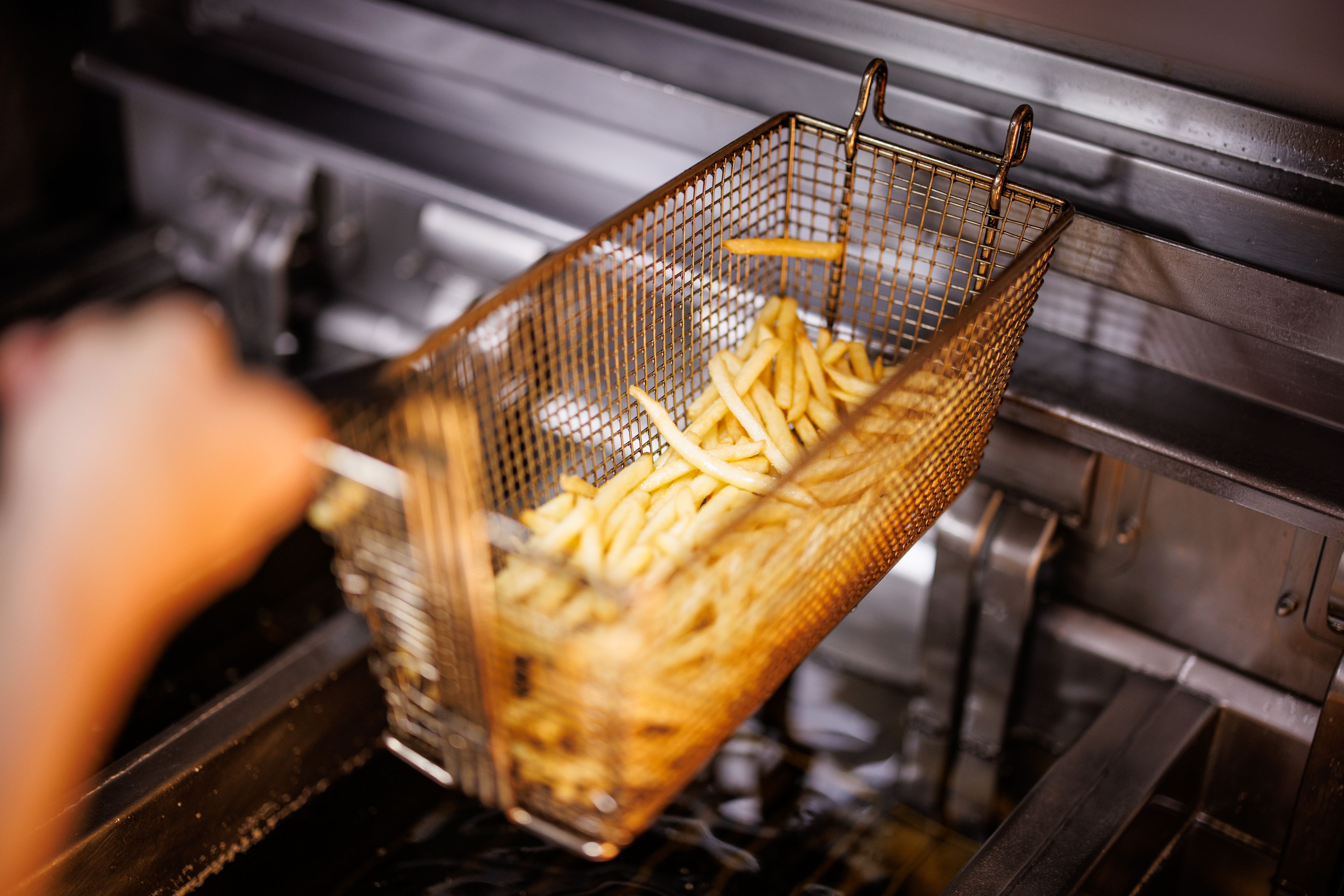 Download von www.picturedesk.com am 22.04.2022 (12:12).  02 December 2021, Bavaria, Munich: An employee takes a basket of French fries out of the fryer at a branch of the McDonald's fast food chain on Martin-Luther-Strasse in Giesing. The branch opened its doors on 4 December 1971 as the first McDonald's branch in Germany. Photo: Matthias Balk/dpa - 20211202_PD17887 - Rechteinfo: Rights Managed (RM)