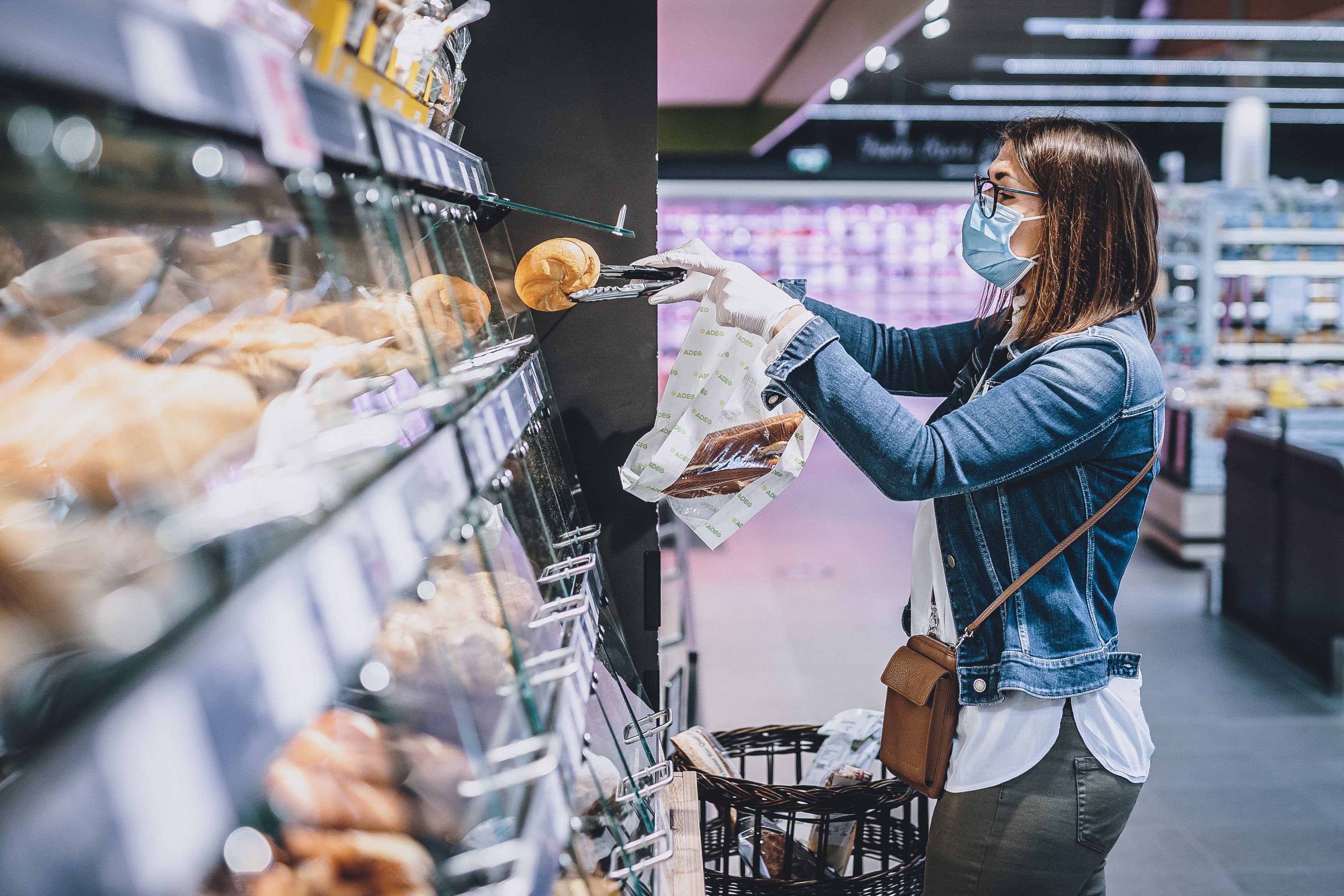 Eine Frau trägt eine Schutzmaske und Handschuhe bei ihrem Einkauf in einem Supermarkt. (Symbolbild)