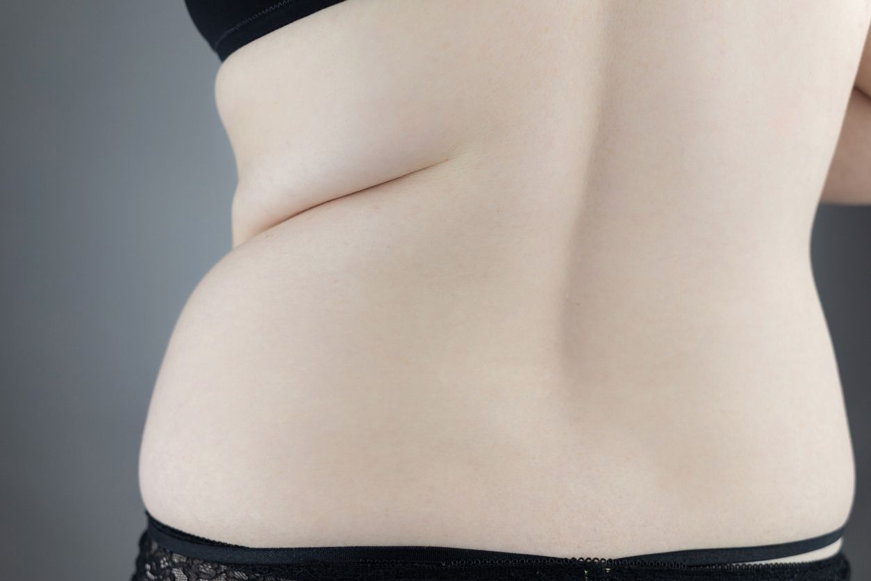 Close-up girl from behind. Side pleats. Excess weight. Adoption non-ideal figure. Body positivity among women. Concept shot. Flowers protrude from underpants, symbolizing acceptance one’s appearance.
