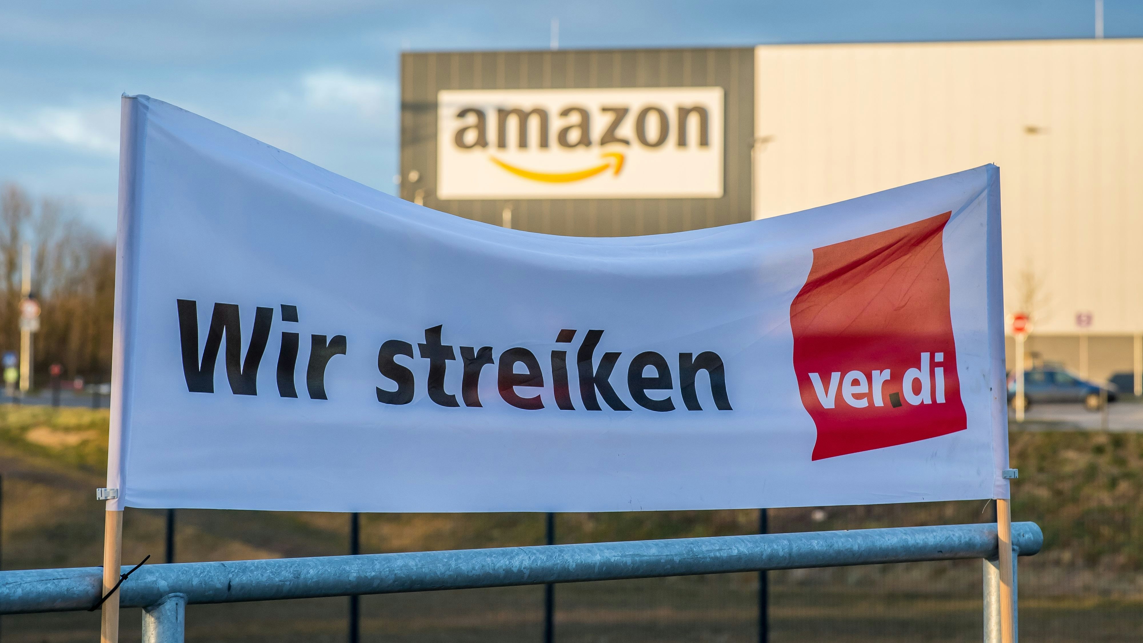 Download von www.picturedesk.com am 02.05.2022 (17:44).  05 March 2018, Germany, Werne: A banner of the labour union Verdi reads 'wir streiken' (lit. 'we're on strike') outside an Amazon logistics centre. Verdi has called for employees to go on strike from 5:30AM on Monday to midnight on Tuesday. Photo: Guido Kirchner/dpa - 20180305_PD2036 - Rechteinfo: Rights Managed (RM)