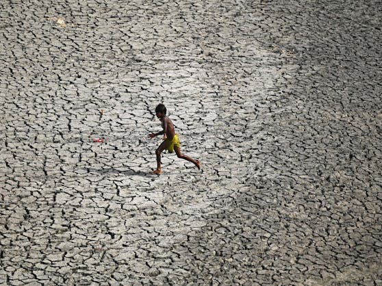 Ein Junge rennt an einem heißen Tag im Frühjahr 2022 in Neu-Delhi über ein ausgetrocknetes Flussbett des Yamuna.