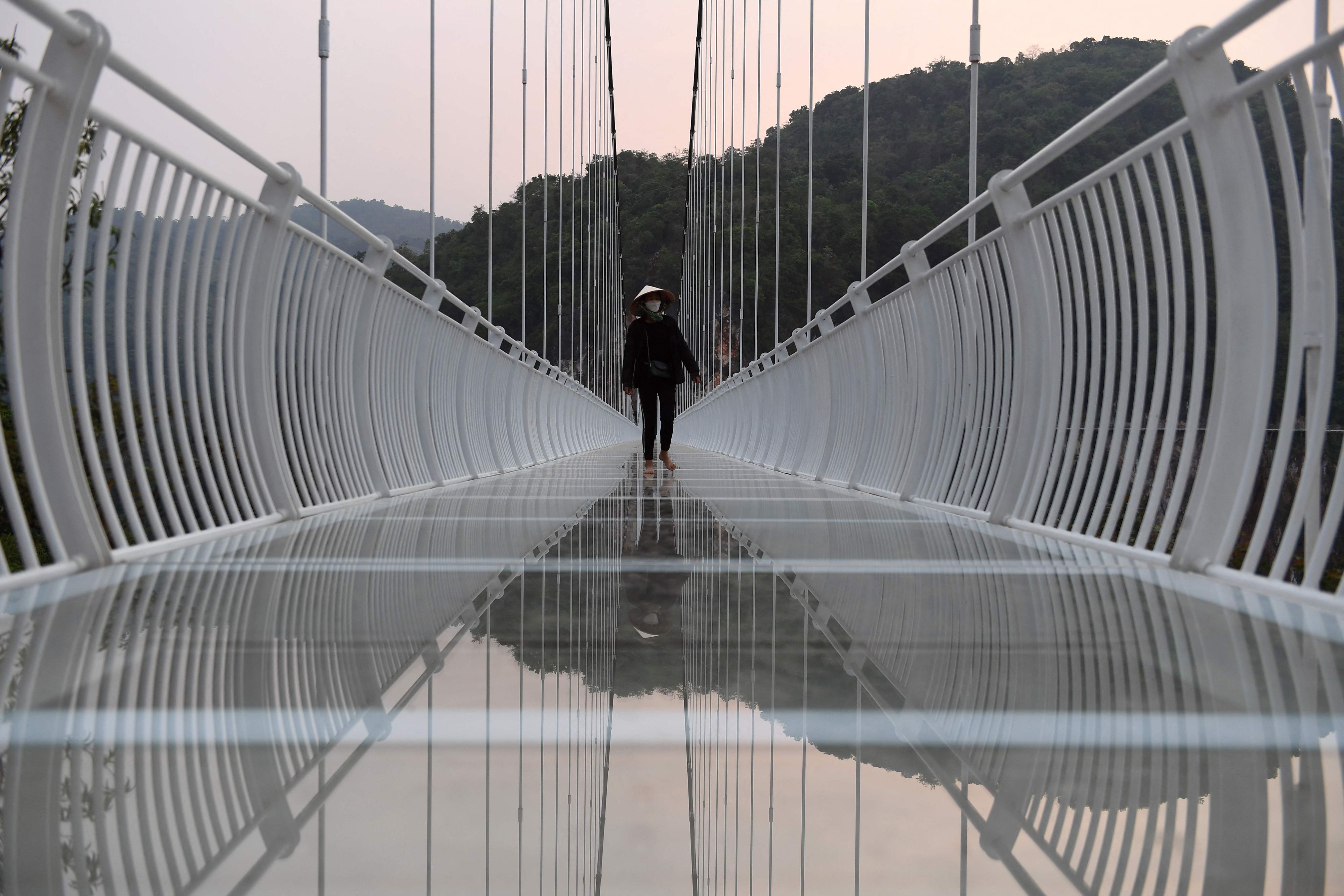 Download von www.picturedesk.com am 03.05.2022 (15:02).  This photo taken on April 28, 2022 shows a staff member walking on the Bach Long glass bridge in Moc Chau district in Vietnam's Son La province. - Vietnam launched a new attraction for tourists -- with a head for heights -- on April 29 with the opening of a glass-bottomed bridge suspended some 150 metres above a lush, jungle-clad gorge. (Photo by Nhac NGUYEN / AFP) - 20220428_PD16418 - Rechteinfo: Rights Managed (RM) Nur für redaktionelle Nutzung! Werbliche Nutzung erfordert Freigabe: bitte schicken Sie uns eine Anfrage.