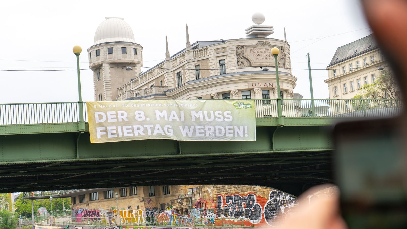 Die Grüne Jugend will dass der 8. Mai ein gesetzlicher Feiertag wird. Dazu hisste man ein Transparent auf der Aspernbrücke in Wien.