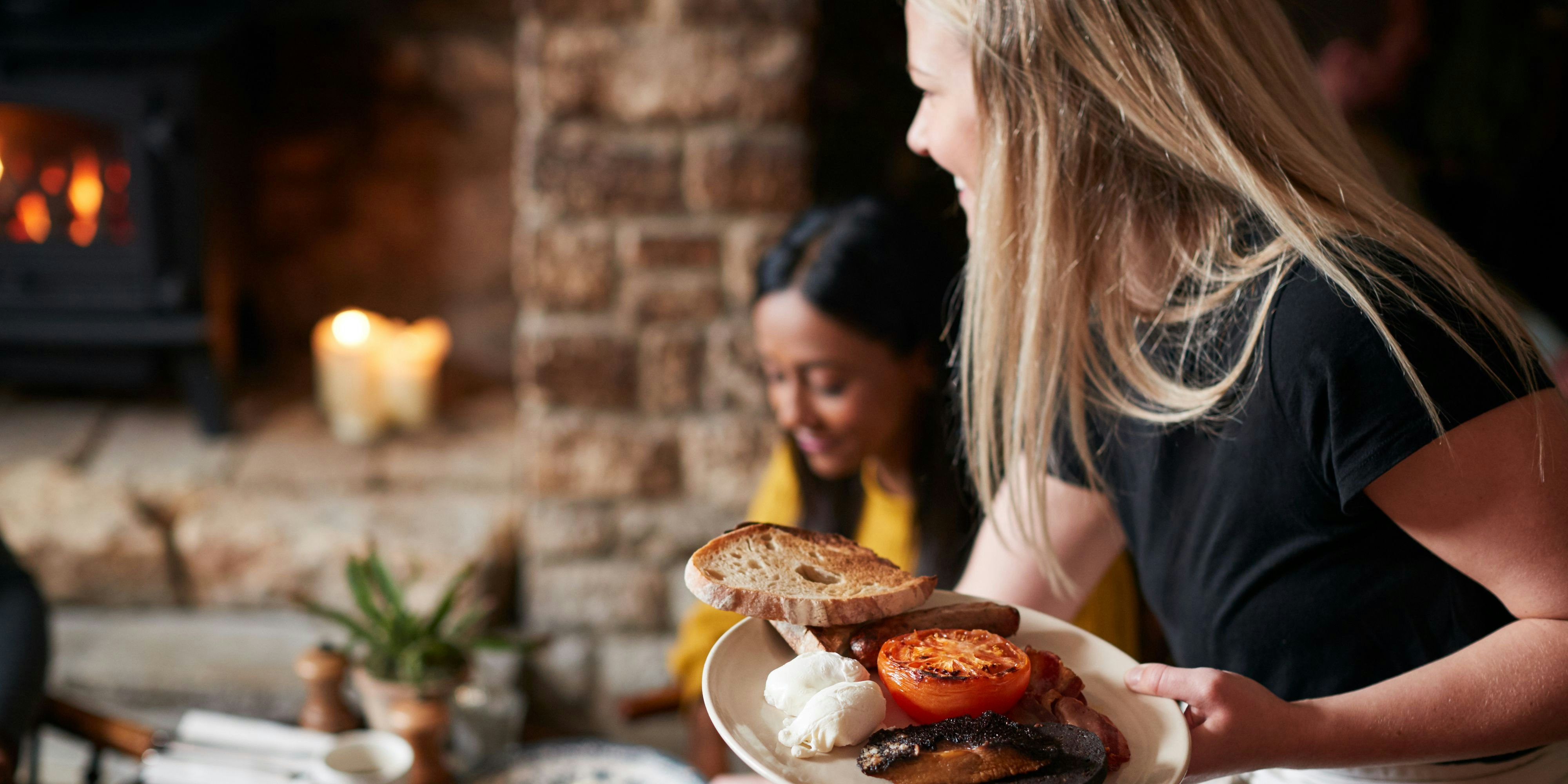 Close Up Of Waitress Working In Traditional English Pub Serving Breakfast To Guests