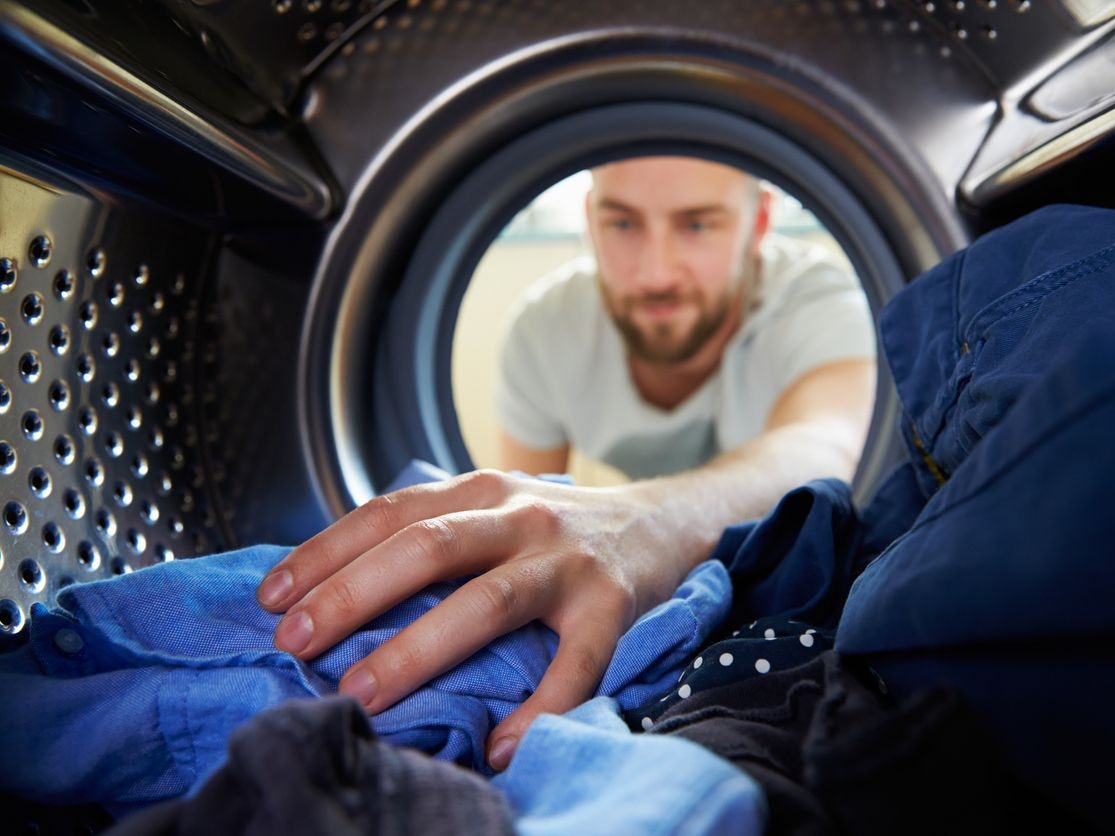 Man Doing Laundry Reaching Inside Washing Machine