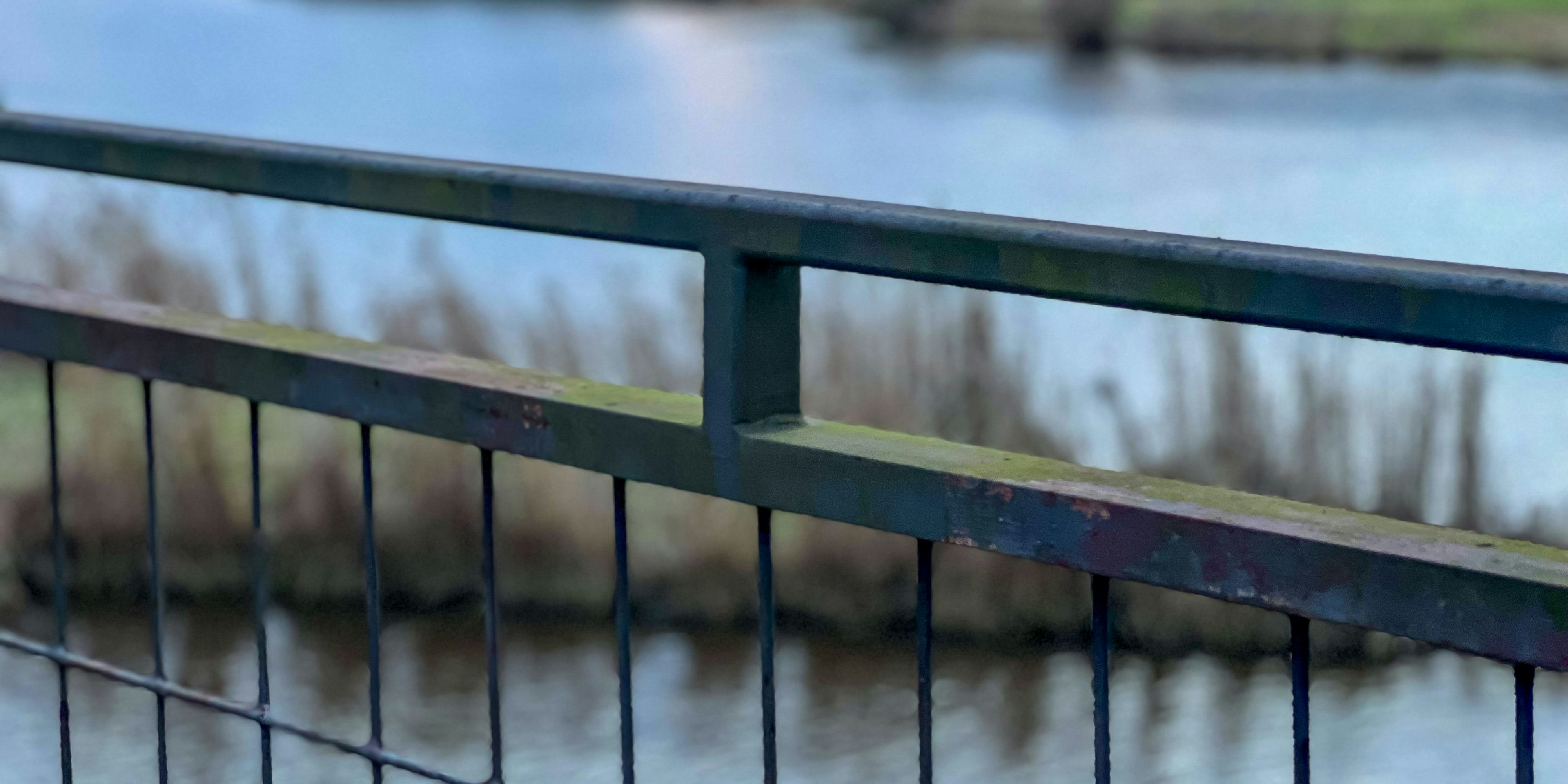 A bridge railing with a beautiful river in the background.