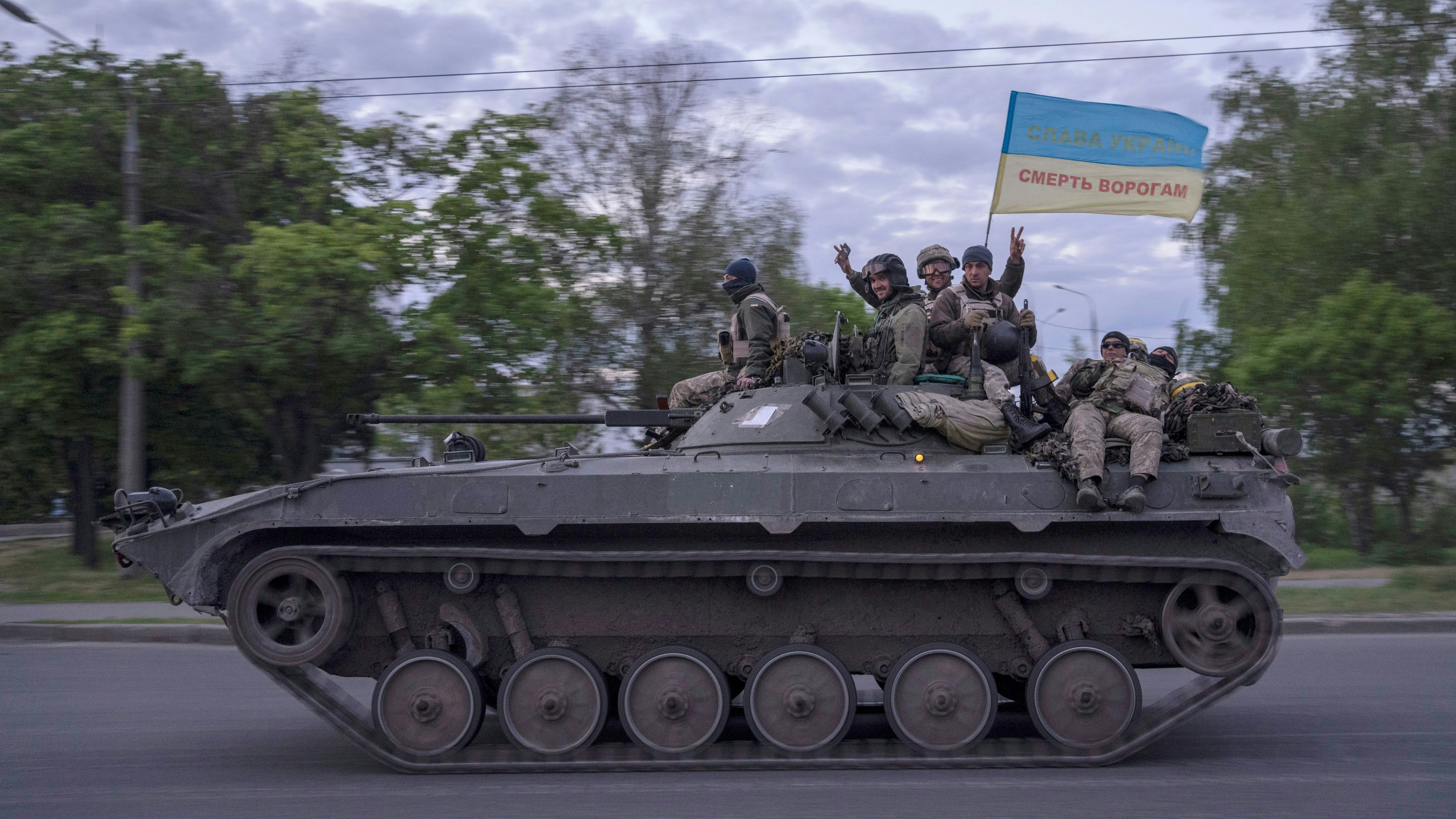 Download von www.picturedesk.com am 17.05.2022 (16:03).  Ukrainian serviceman wave a flag with writing reading in Ukrainian "Glory to Ukraine", top, and "Death to the enemies" as they ride atop of a tank in the Kharkiv region, eastern Ukraine, Monday, May 16, 2022. (AP Photo/Bernat Armangue) - 20220516_PD12136 - Rechteinfo: Rights Managed (RM)