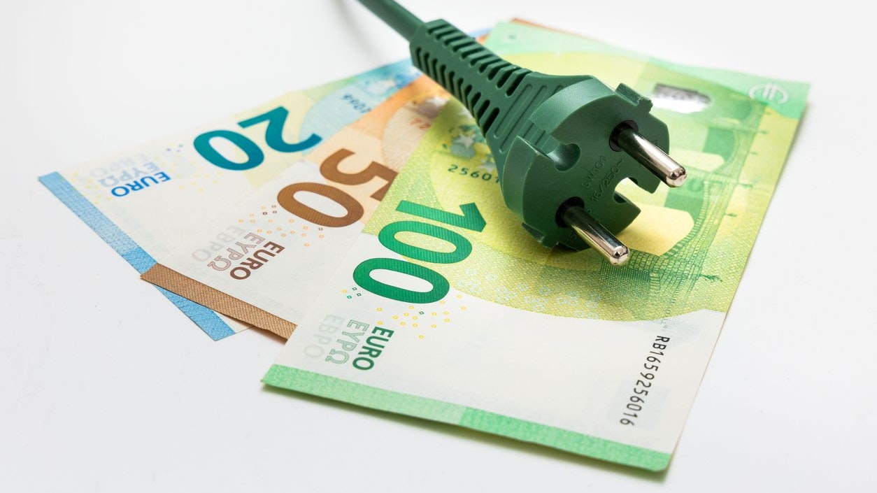 Green plug on euro banknotes - on white background Renewable energy and finance concept