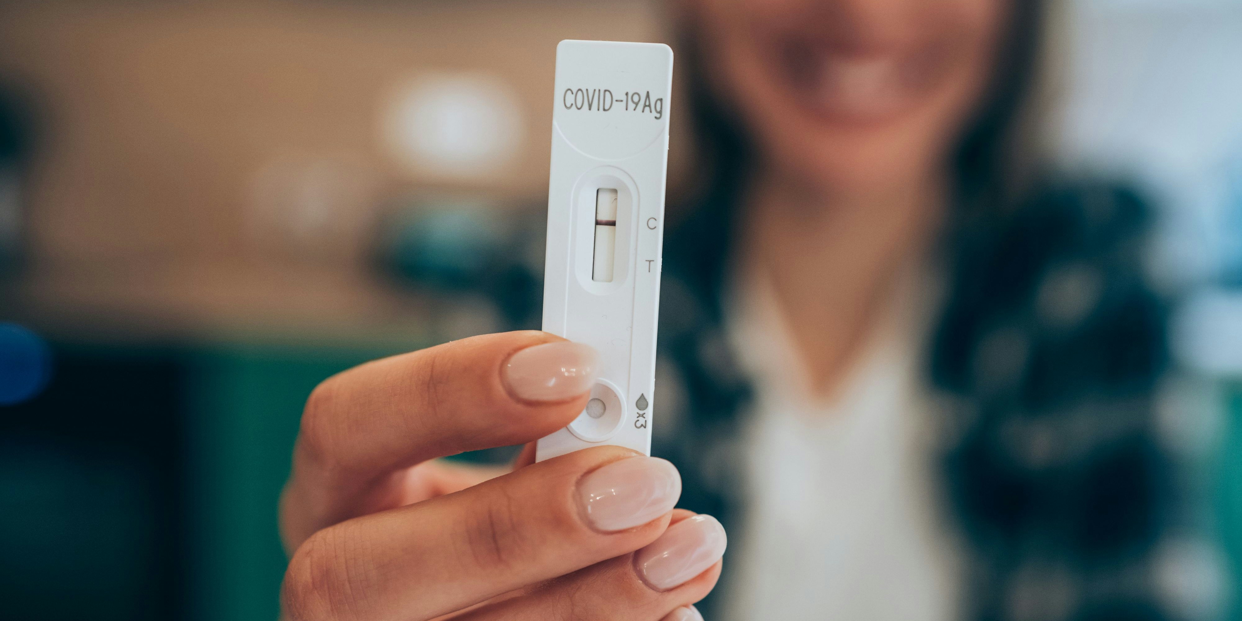 Close-up shot of woman's hand holding a negative test device. Happy young woman showing her negative Coronavirus/Covid-19 rapid test. Focus is on the test.