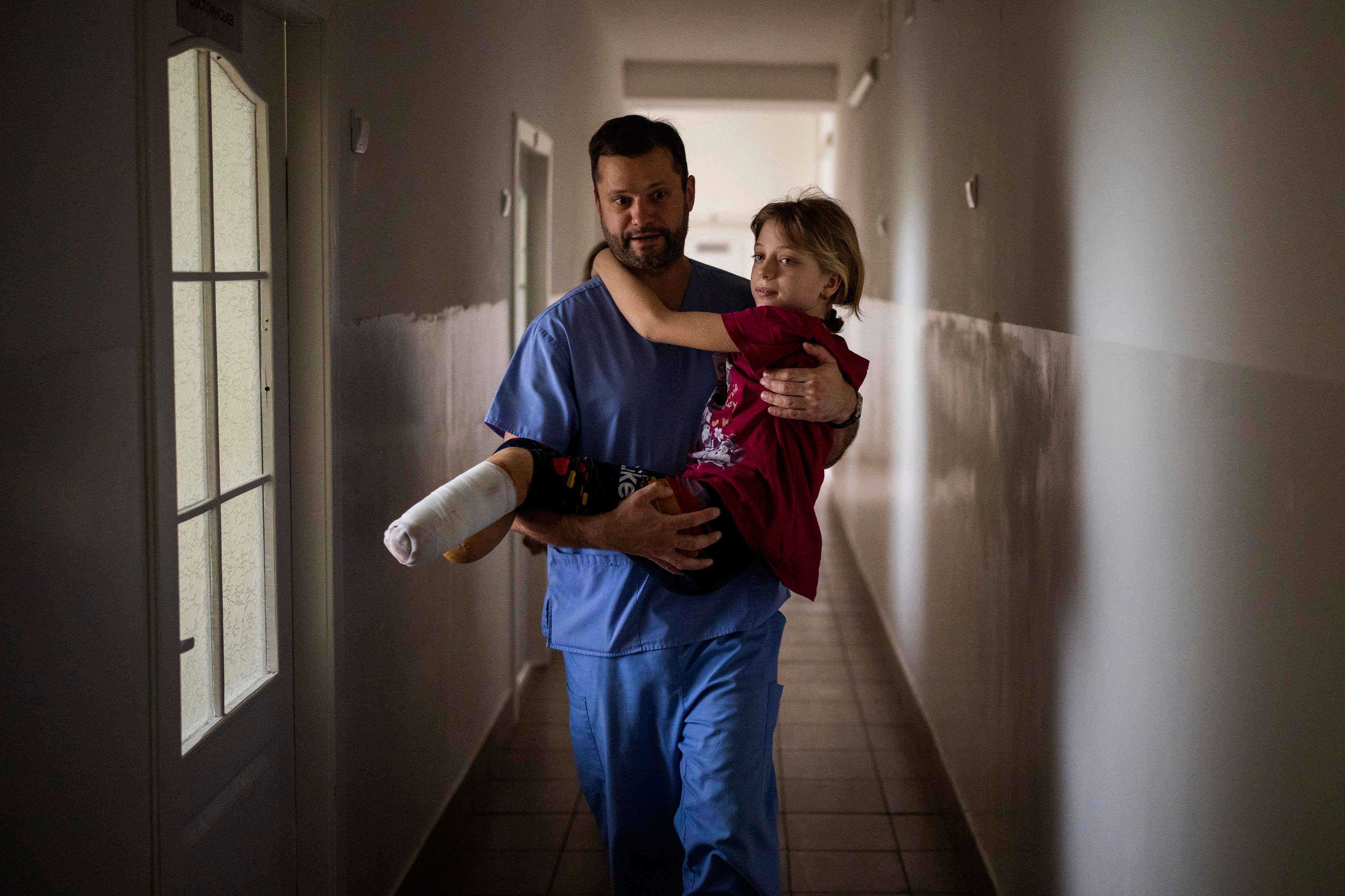 Download von www.picturedesk.com am 19.05.2022 (09:43).  Yana Stepanenko, 11, is carried by a doctor at a public hospital in Lviv, Ukraine, Friday, May 13, 2022. Yana and her mother Natasha, 43, were injured April 8 during shelling at the train station of the eastern city of Kramatorsk where they travelled with Yana's twin brother Yarik from their village near the front line. They were planning to catch an evacuation train heading west and, they hoped, to safety. (AP Photo/Emilio Morenatti) - 20220513_PD14577 - Rechteinfo: Rights Managed (RM)