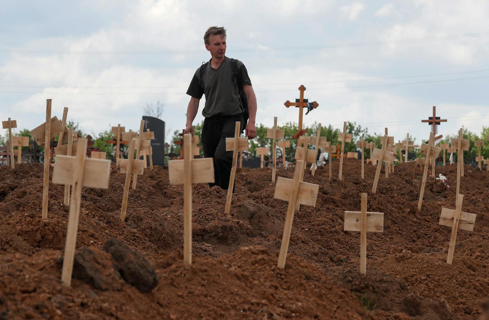 Ein Mann zwischen frisch ausgehobenen Gräbern auf einem Friedhof in der Siedlung Staryi Krym außerhalb von Mariupol, Ukraine, am 15. Mai 2022.