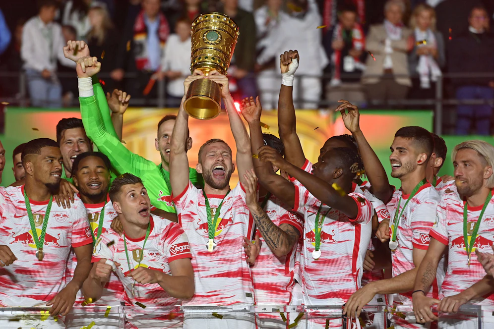 Konrad Laimer stemmt den DFB-Pokal in den Berliner Abendhimmel.