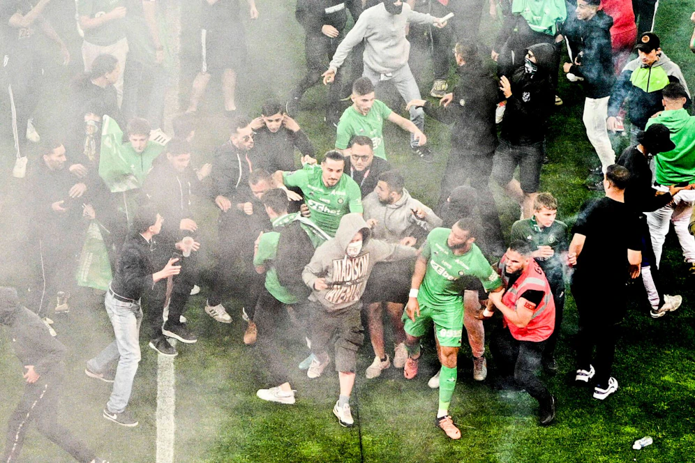 Etienne-Hooligans stürmen den Rasen und machen Jagd auf die eigenen Spieler.
