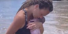 Frau gebärt ihr Kind ohne Hilfe in der Meeresbrandung