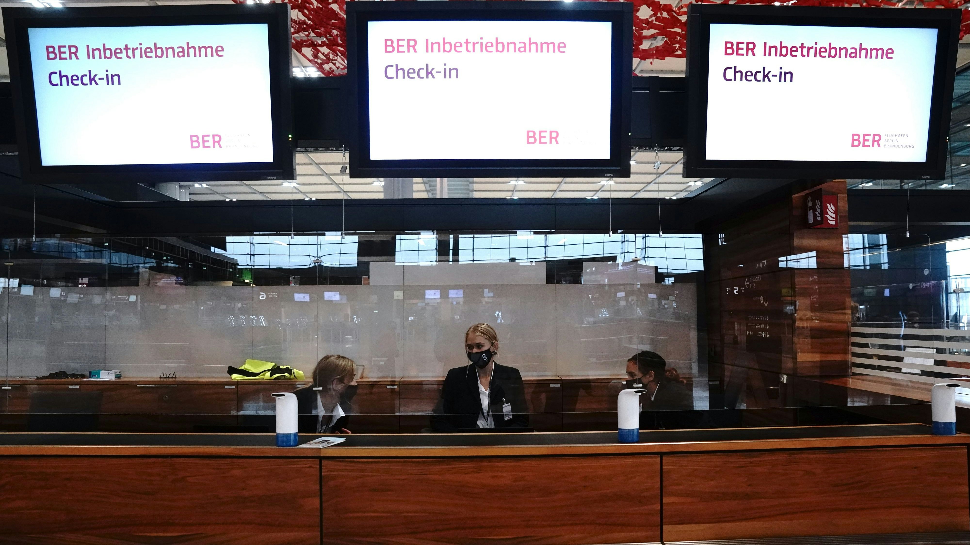 Download von www.picturedesk.com am 03.06.2022 (15:59).  31 October 2020, Berlin, Schönefeld: Aircraft port employees sit at the counter under monitors with the inscription "BER Inbetriebnahme - Check in" (BER) at Terminal 1 of the Berlin Brandenburg Airport "Willy Brandt" (BER). After a long delay, the airport will be opened on 31.10.2020. Photo: Kay Nietfeld/dpa - 20201031_PD4478 - Rechteinfo: Rights Managed (RM)