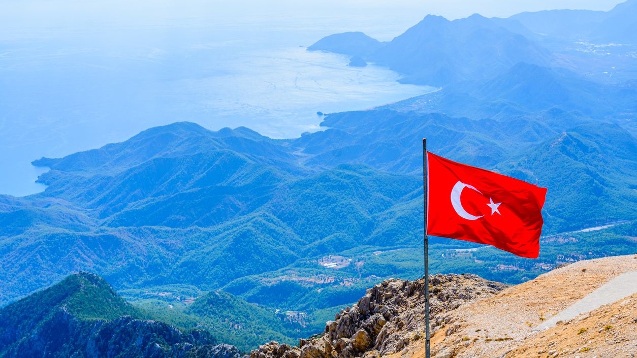 View on Mediterranean sea and hills from summit of Tahtali mountain. Turkish flag on foreground