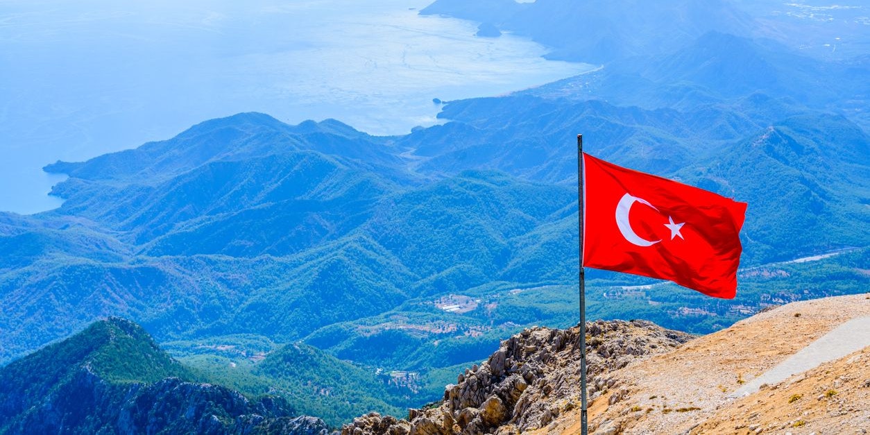 View on Mediterranean sea and hills from summit of Tahtali mountain. Turkish flag on foreground
