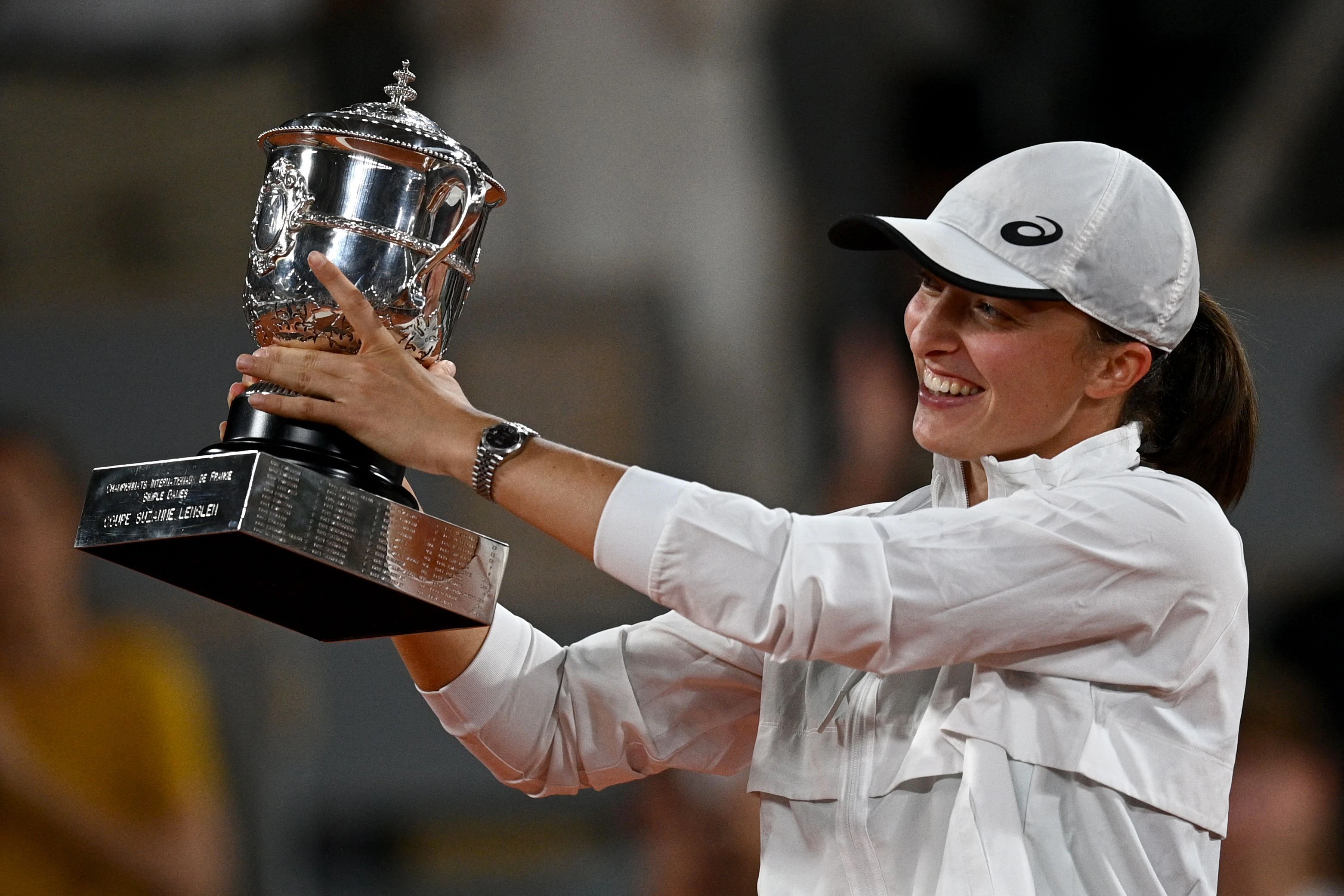 Iga Swiatek strahlt mit der Trophäe von Roland Garros um die Wette.
