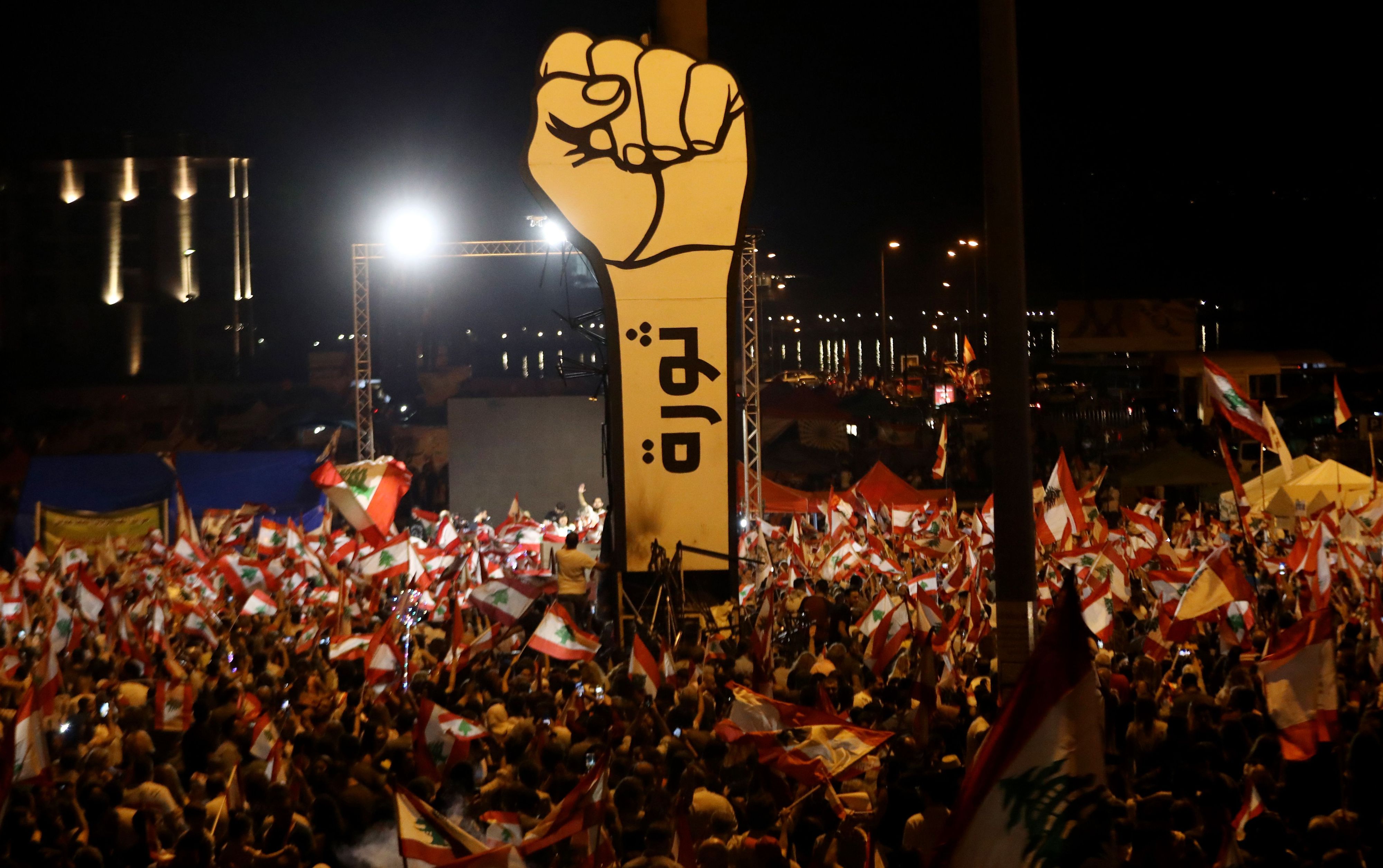 Download von www.picturedesk.com am 15.06.2022 (11:33).  (FILES) In this file photo taken on November 10, 2019, Lebanese demonstrators wave national flags during ongoing anti-government protests in the heart of Beirut, with an Arabic slogan on the fist in the background reading "Revolution". - The Arab Spring uprisings are nearly a decade-old and moribund but protests in Lebanon and three other new countries last year revealed that the spirit of the revolts that lit up 2011 is still alive. The countries swept up by the latest revolts had initially stood on the sidelines as a contagion of uprisings gripped countries in the Middle East and North Africa in 2011. But in 2019 they led calls for an end to the same regional economic precariousness, corruption, and unresponsive governance that fuelled the Arab protests years earlier. (Photo by ANWAR AMRO / AFP) - 20191110_PD21175 - Rechteinfo: Rights Managed (RM) Nur für redaktionelle Nutzung! Werbliche Nutzung erfordert Freigabe: bitte schicken Sie uns eine Anfrage.