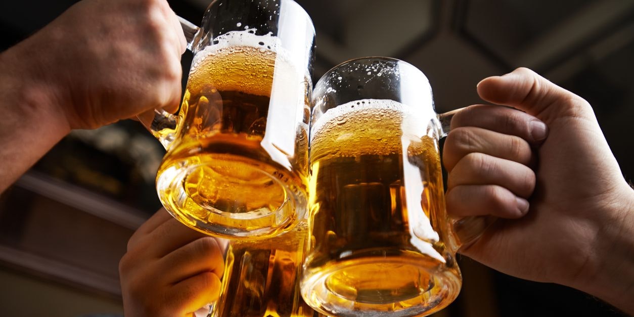 Hands of three men toasting with beer