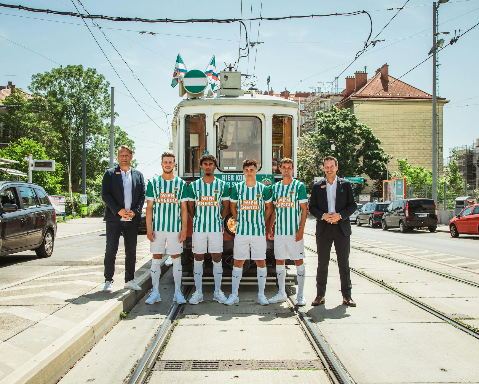 Das neue Rapid-Heimtrikot. Die Spieler posieren gemeinsam mit den Geschäftsführern vor der Straßenbahnlinie 49.