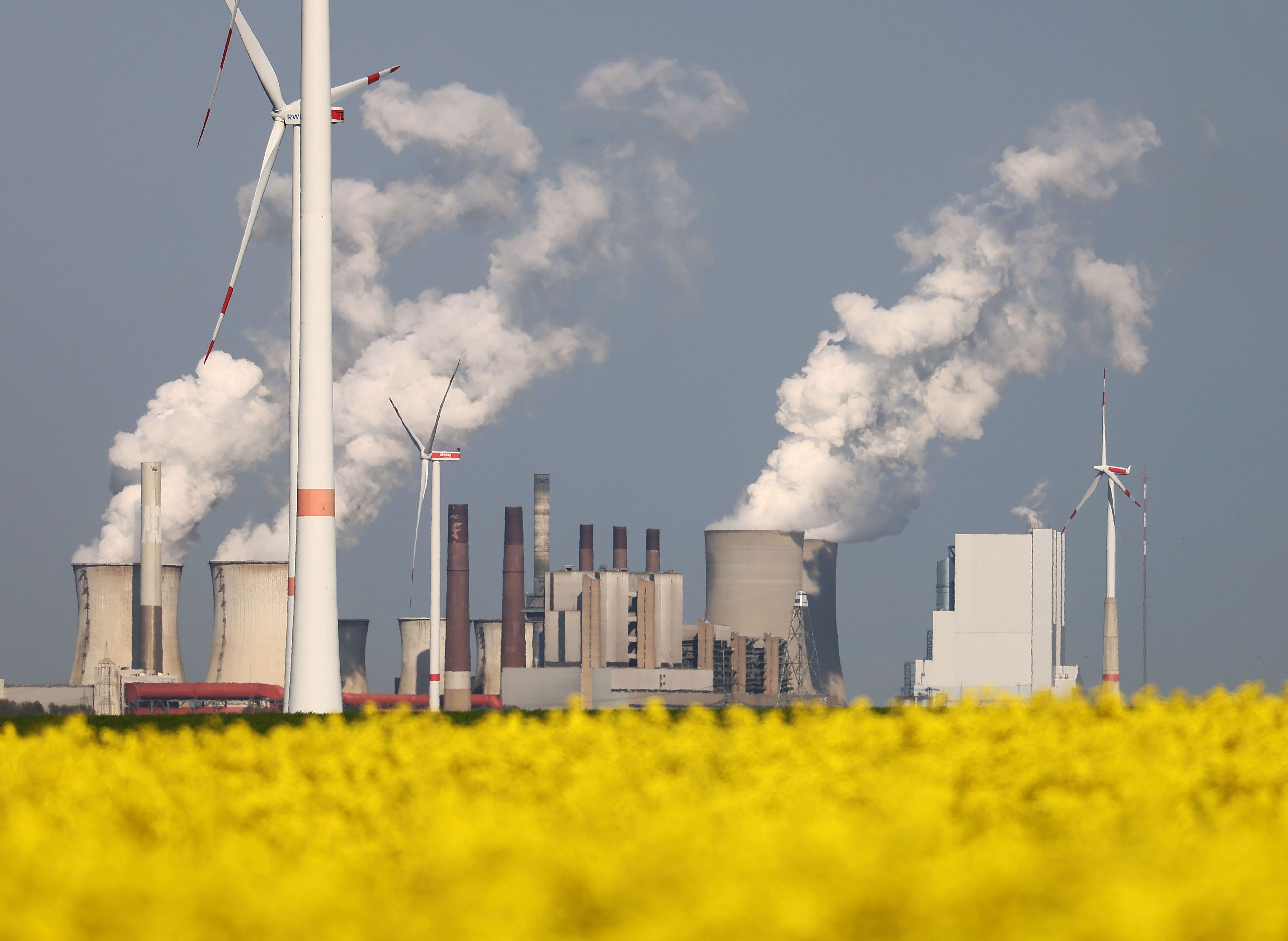 Download von www.picturedesk.com am 20.06.2022 (11:39).  03 May 2022, North Rhine-Westphalia, Erkelenz: RWE wind turbines rotate behind a rapeseed field at the Garzweiler open pit mine in front of the Neurath power plant. Photo: Oliver Berg/dpa - 20220503_PD18426 - Rechteinfo: Rights Managed (RM)