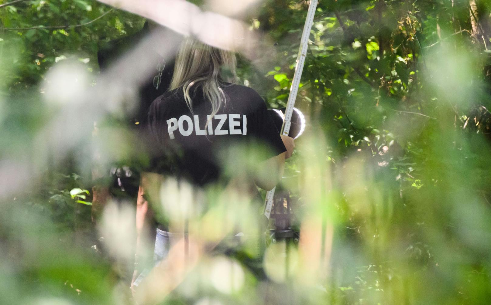 Ein Mitglied des Forensiker-Teams der Salzgitterer Polizei steht an einem Tatort auf einer Grünfläche am Hans-Böckler-Ring, am 22.6.2022.