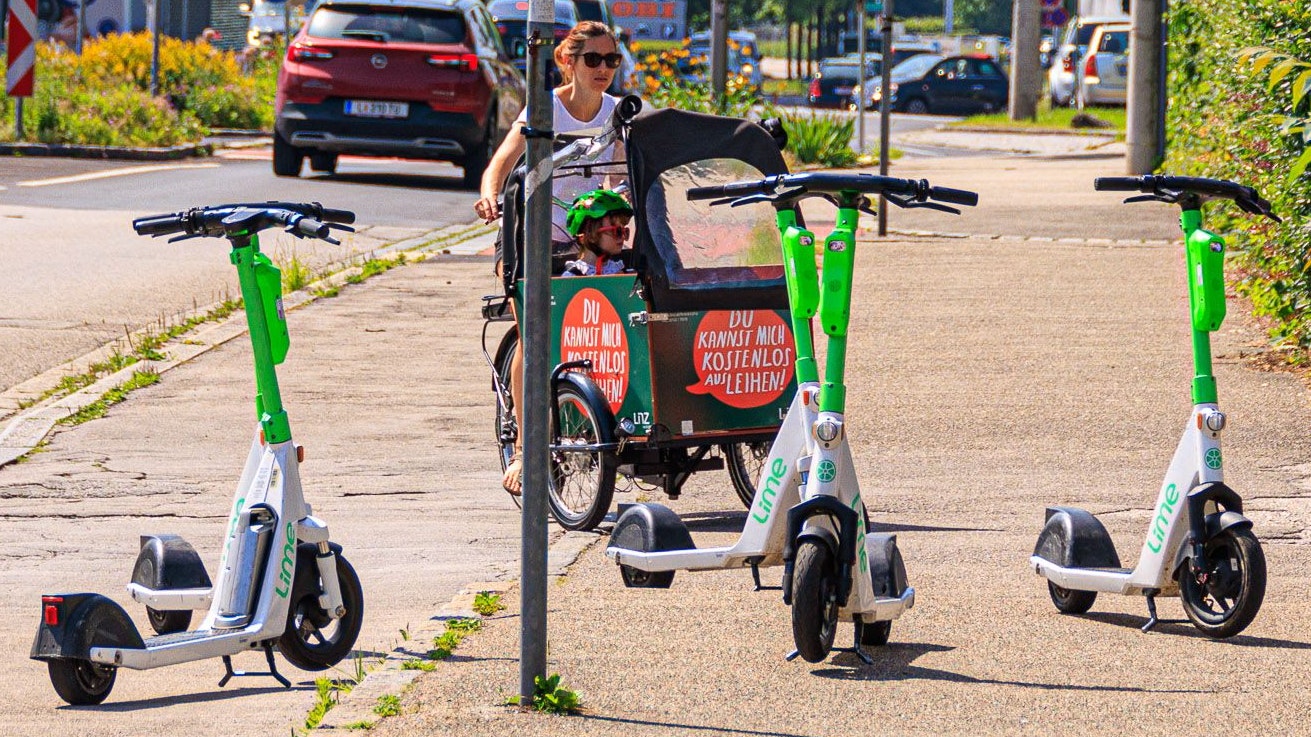 Scooter versperren einer Mutter mit Kind im Lastenrad den Weg