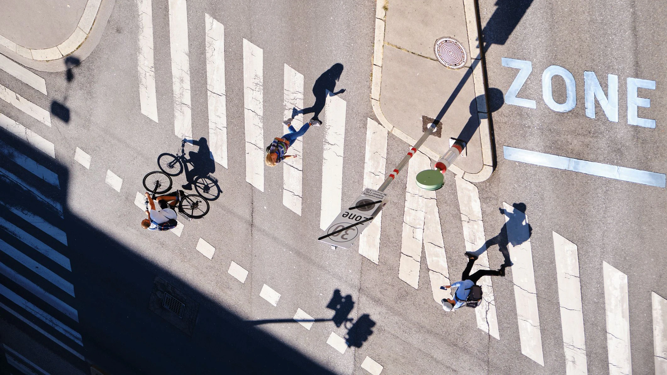 Vienna, Austria - September 13, 2019: Long shadows of people walking and biking at an intersection - aerial view.