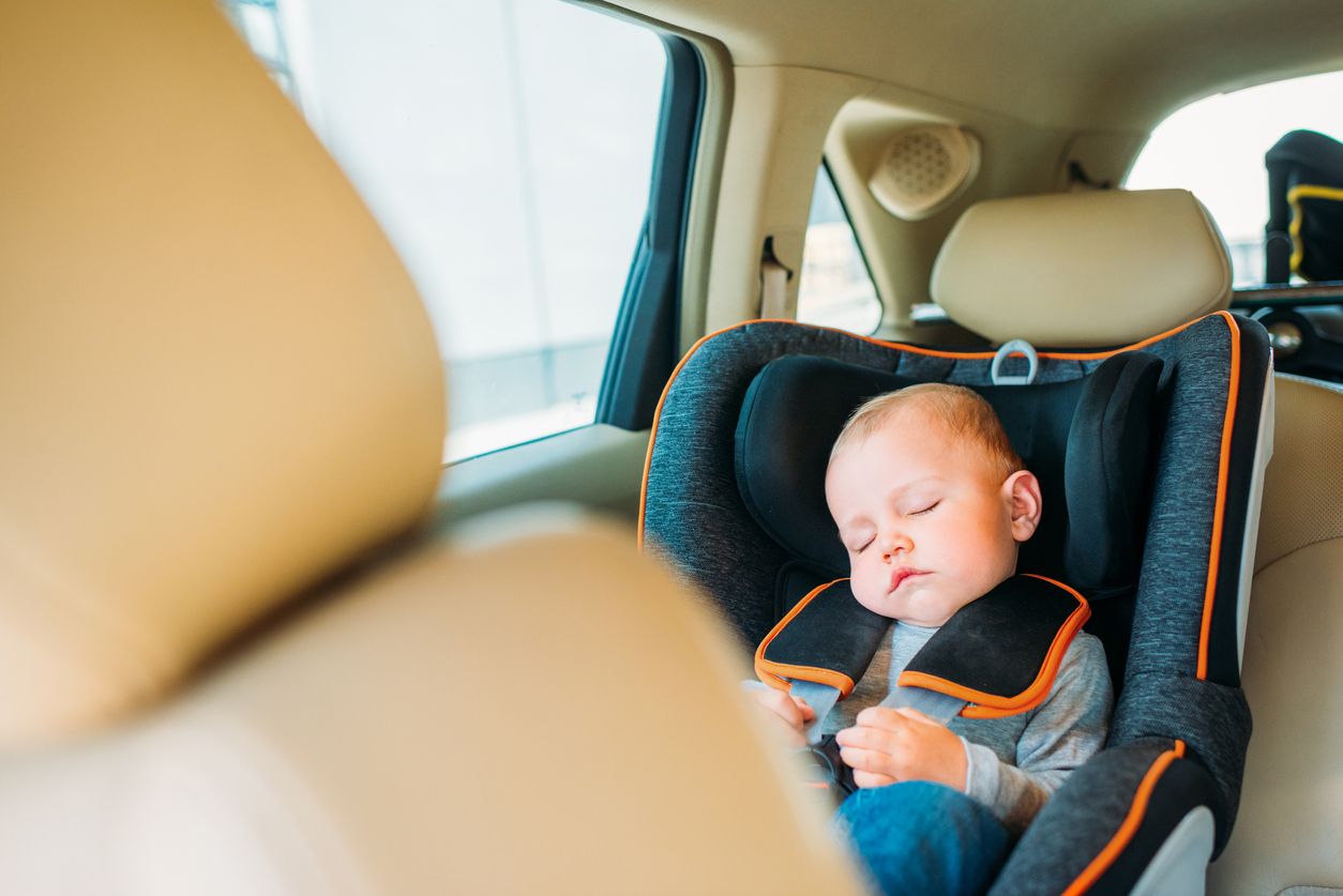 adorable little baby sleeping in child safety seat in car